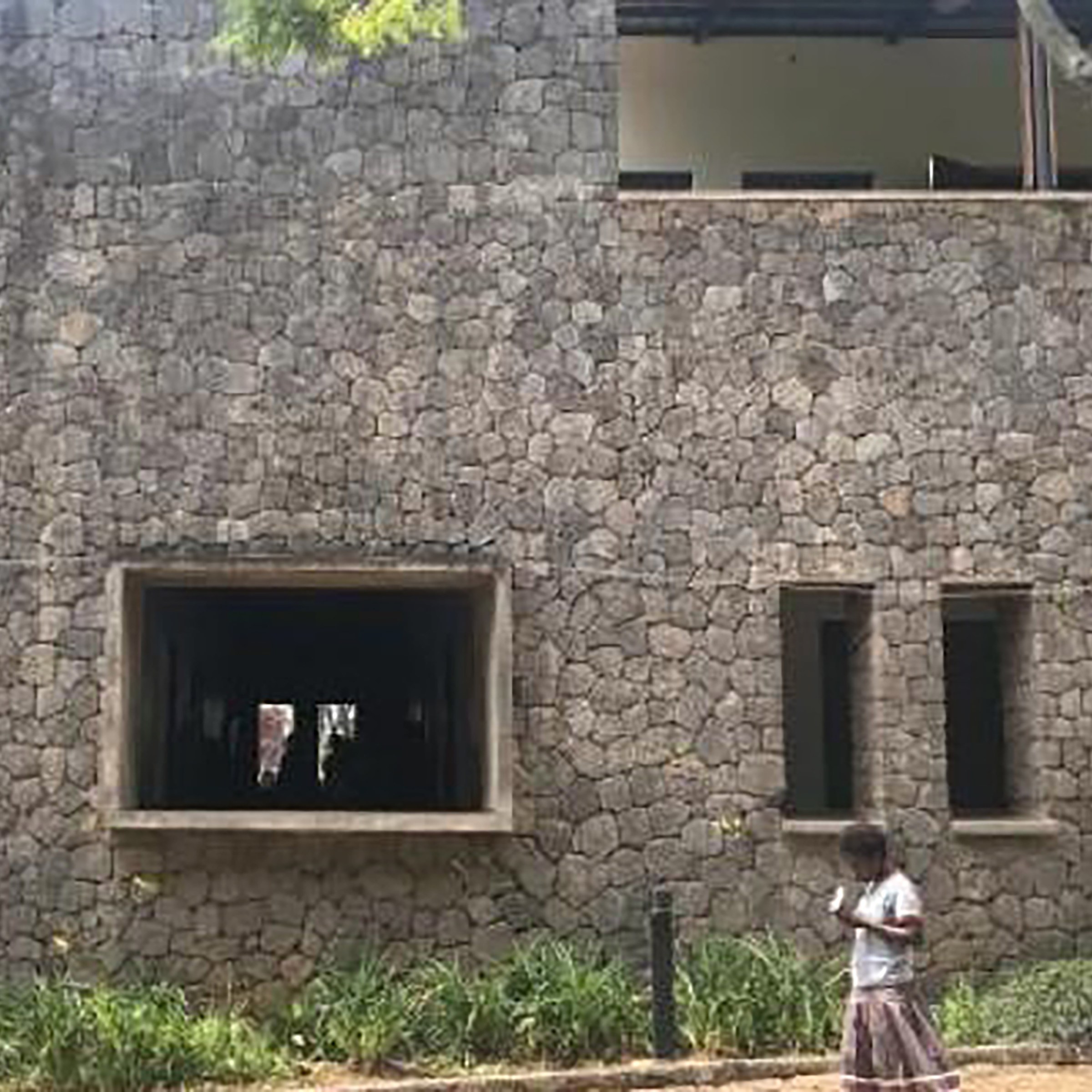 Photo of African woman walking by a cobblestone building