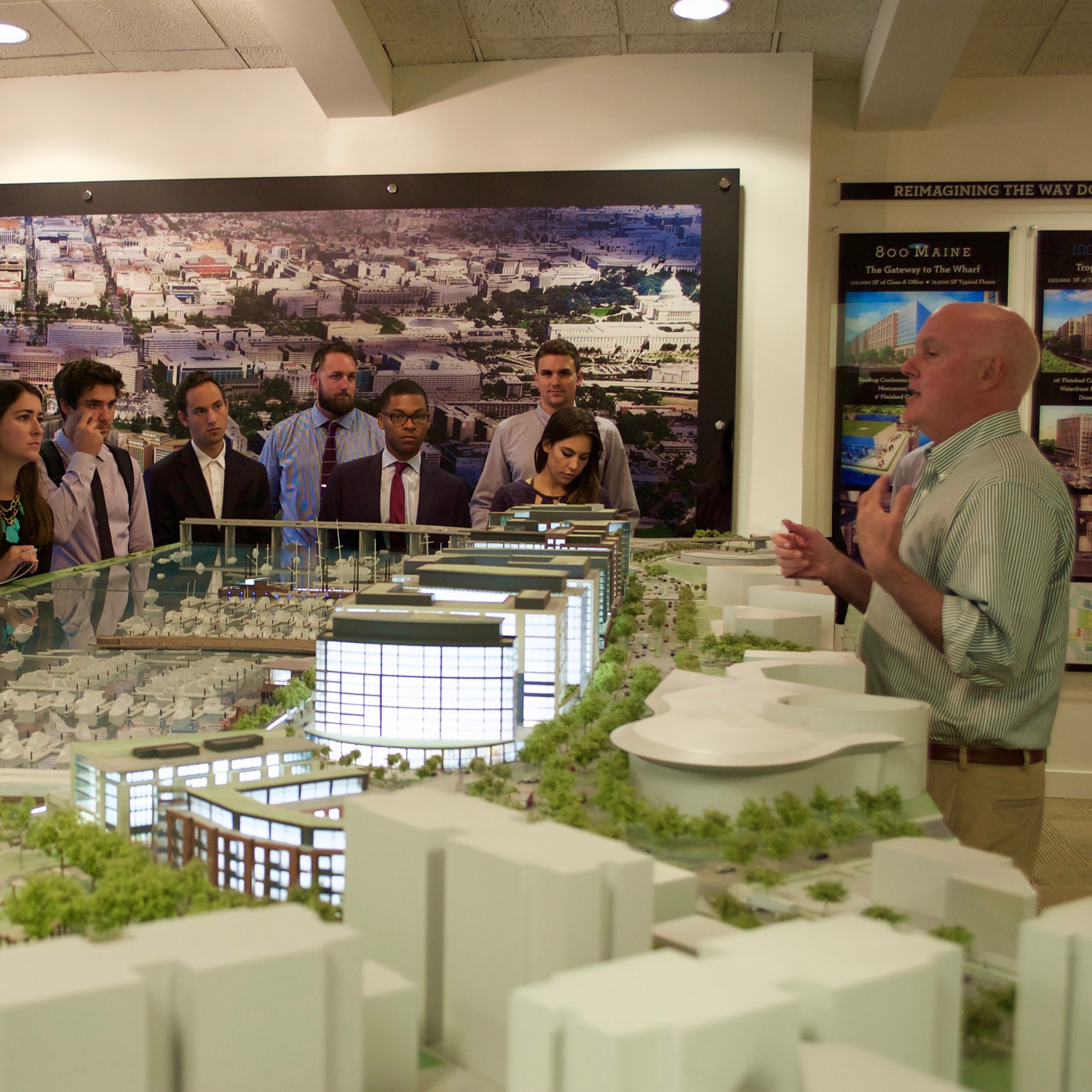 Someone presents to a group of students in front of a model replica