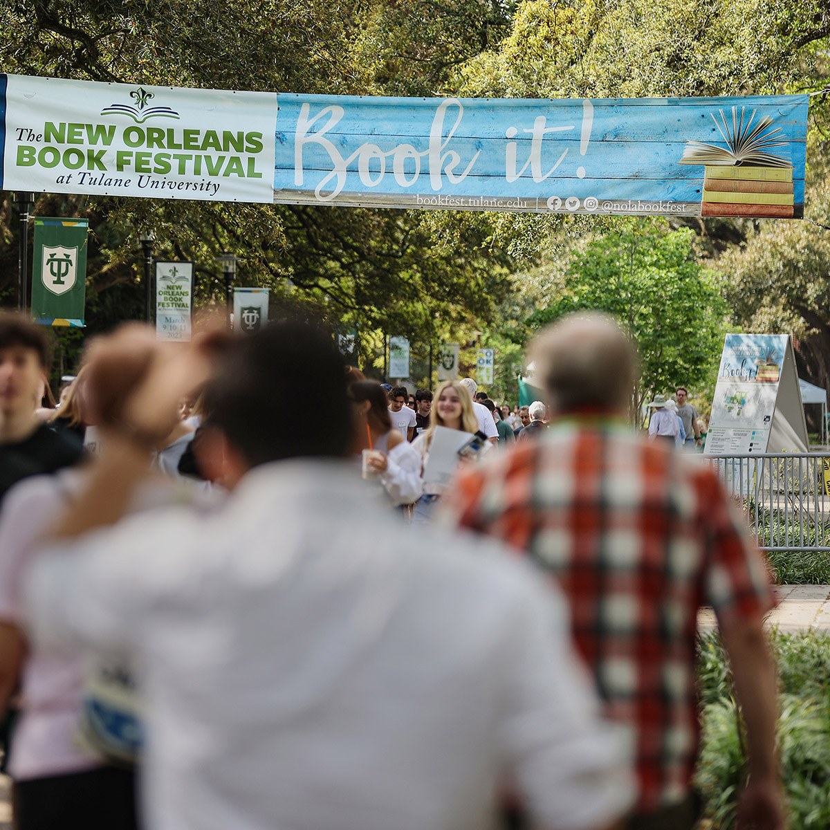 People walking through Tulane's campus under a banner promoting Book Festival 