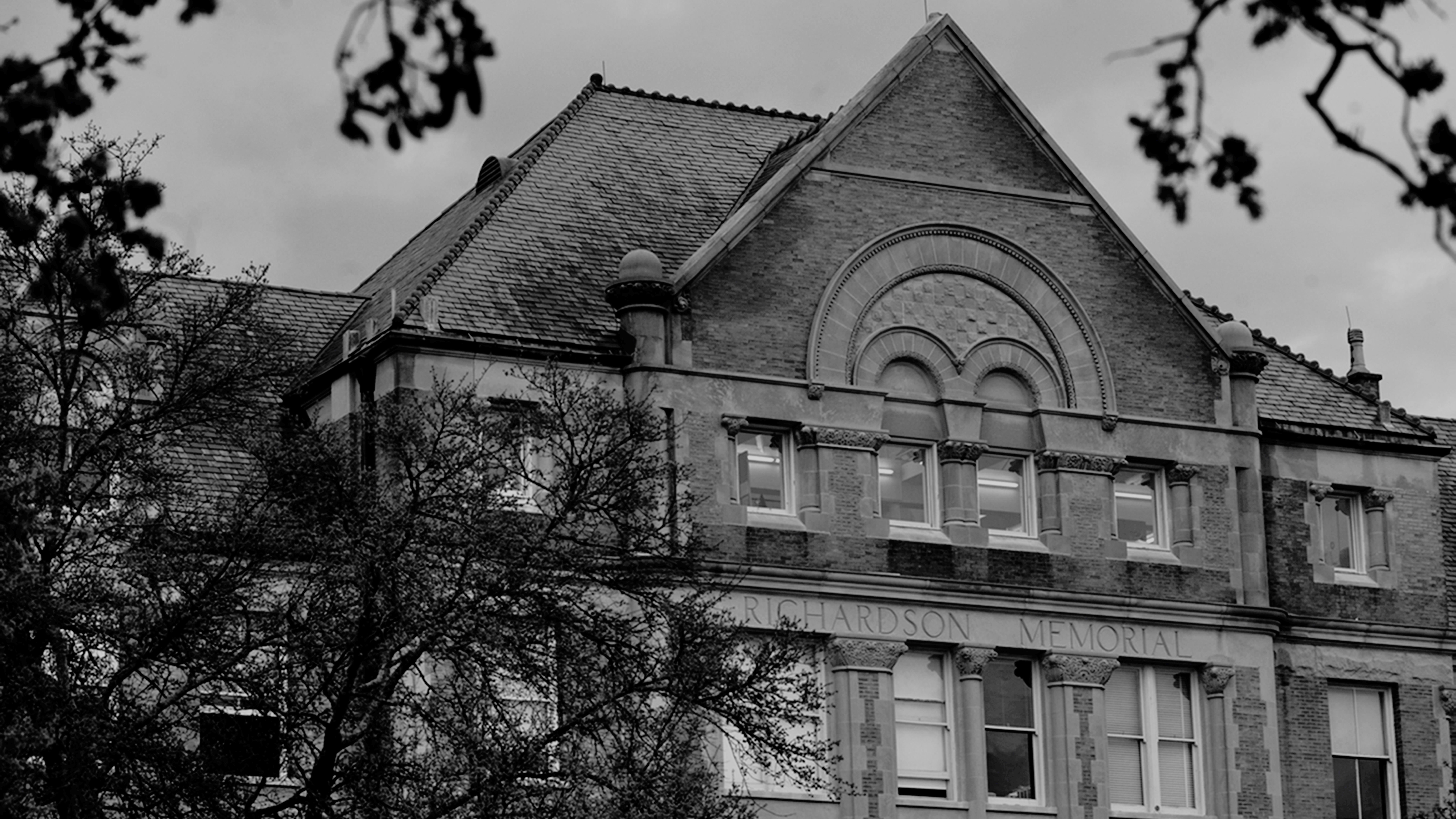 photo of front facade of Richardson Memorial Hall, looking through tree branches in the foreground
