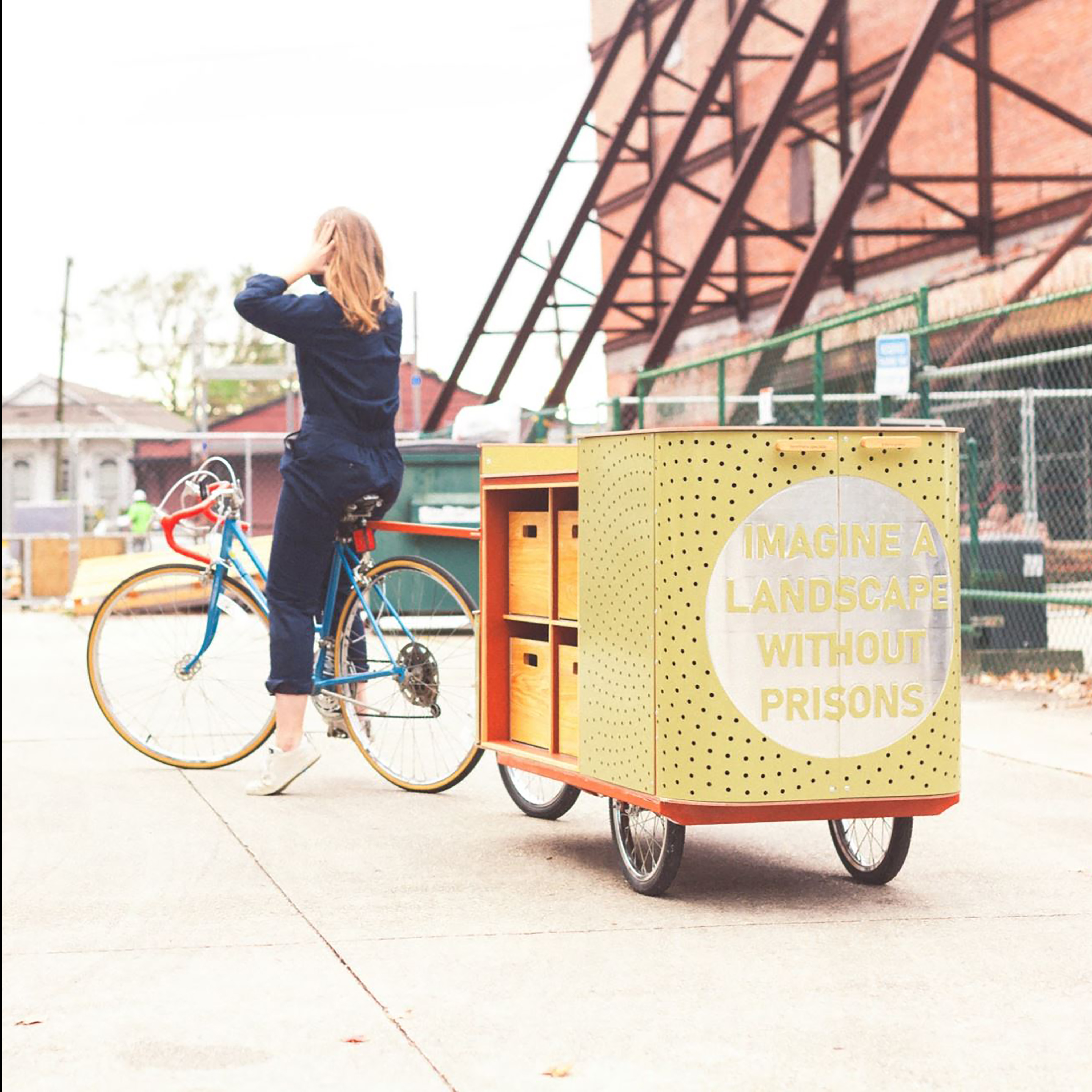 photo from behind of a person riding on a bike-driven cart, called an apothecart, in an empty parking lot in an urban setting
