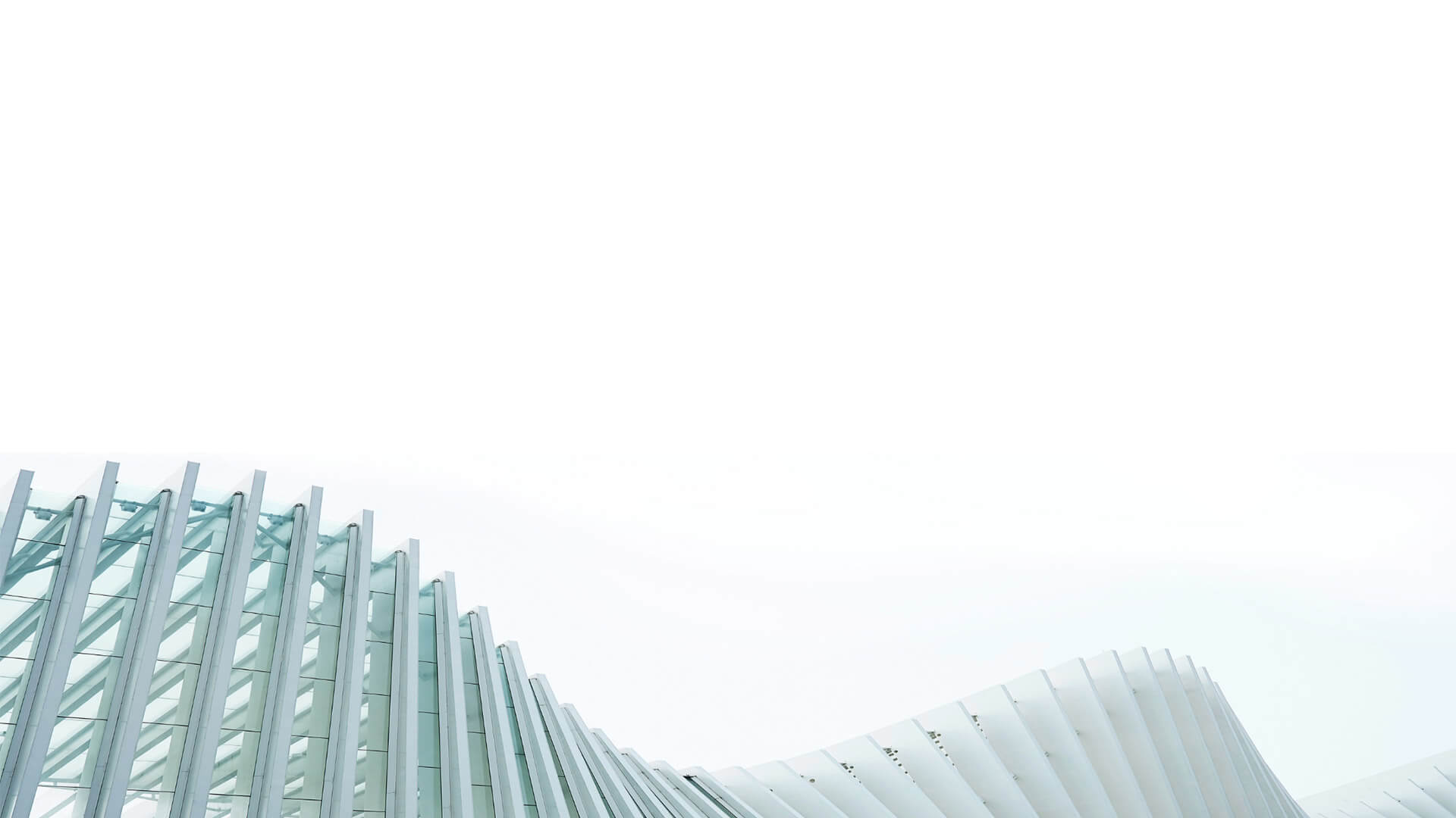 Photo of a curved building facade with beams and windows, looking up to the sky from below the curved structure