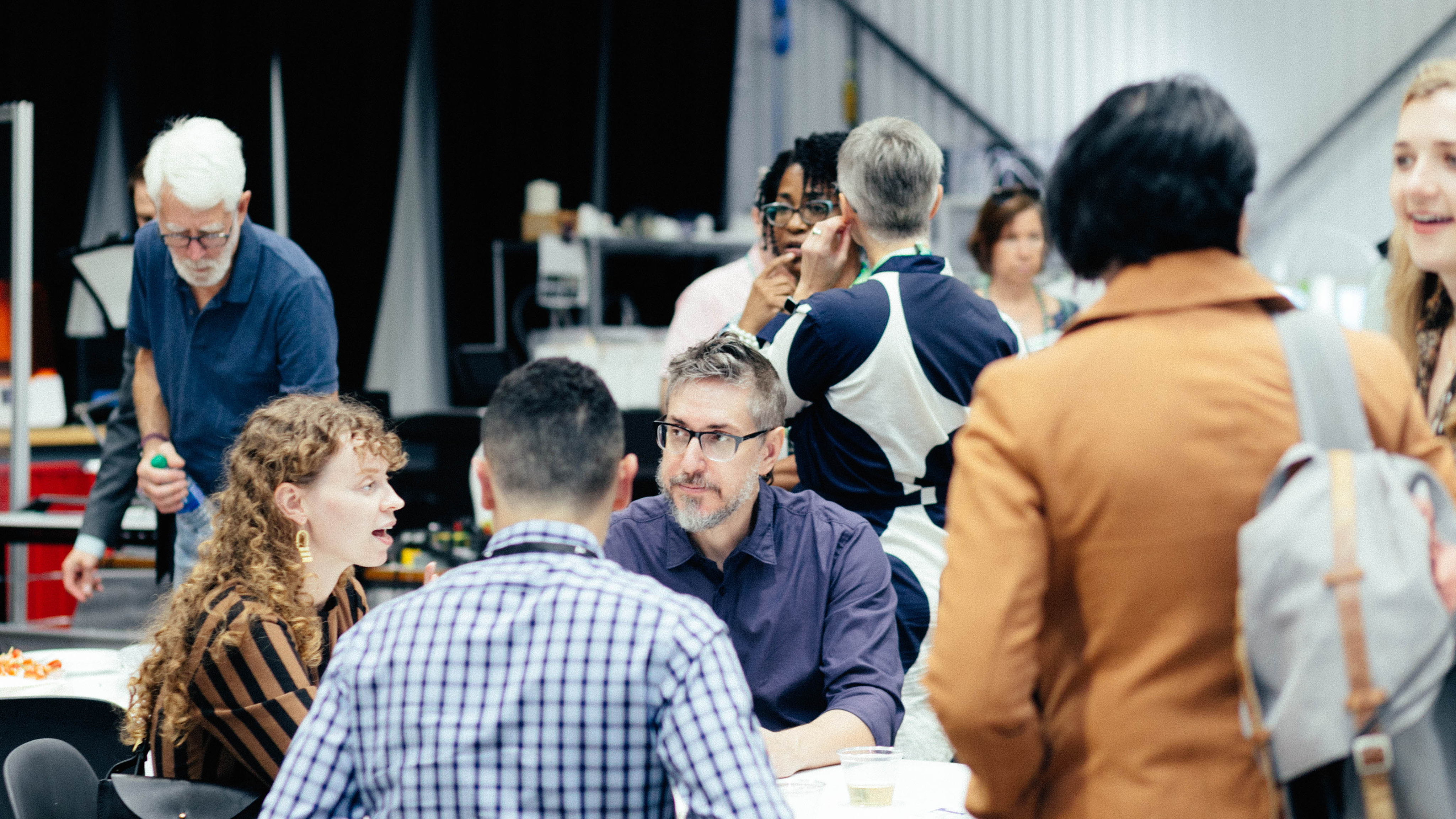 Photo of people talking while sitting and standing during a reception event indoors