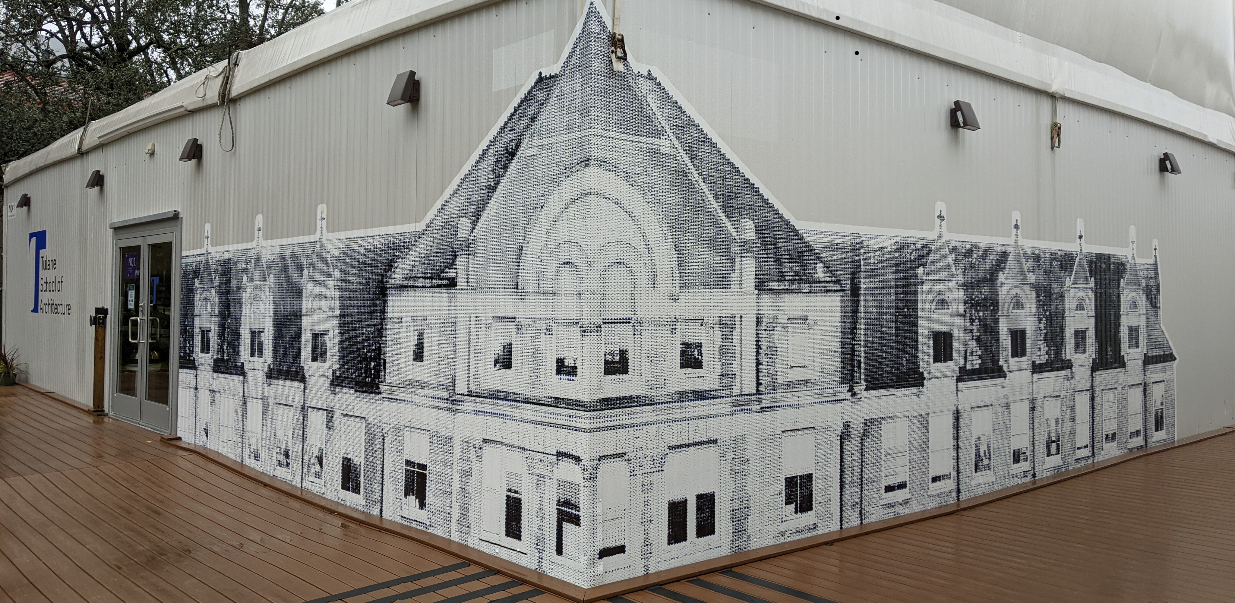 Photo of an exterior corner of a pavilion that has a wrap-around large screen print on the corner, showing a historic building facade