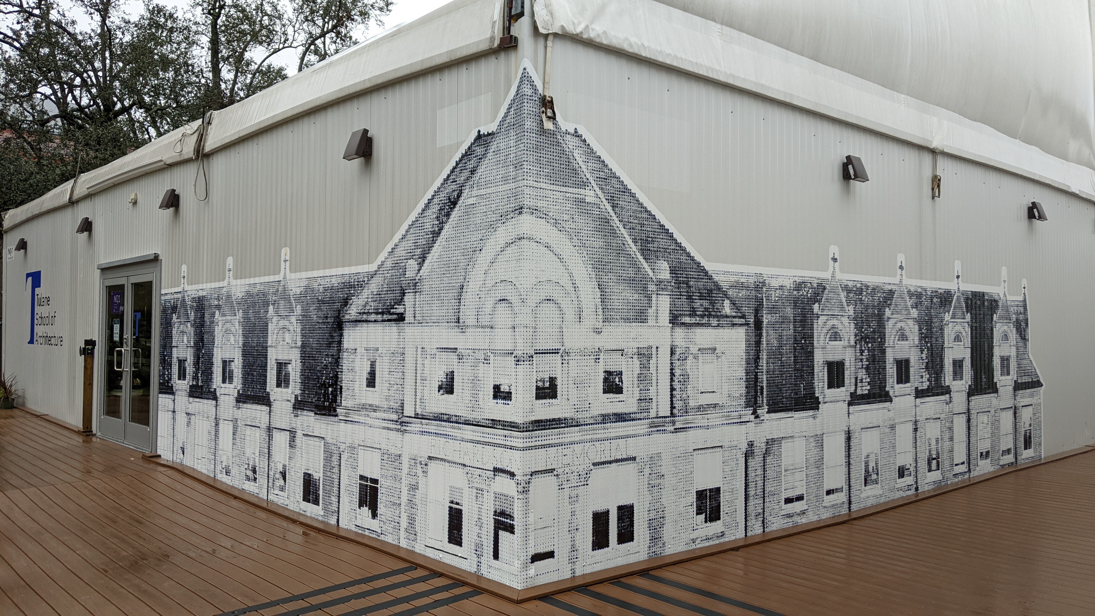 Photo of an exterior corner of a pavilion that has a wrap-around large screen print on the corner, showing a historic building facade
