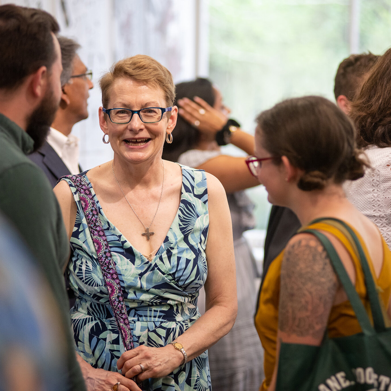 Smiling parent talking to two students inside a reception event