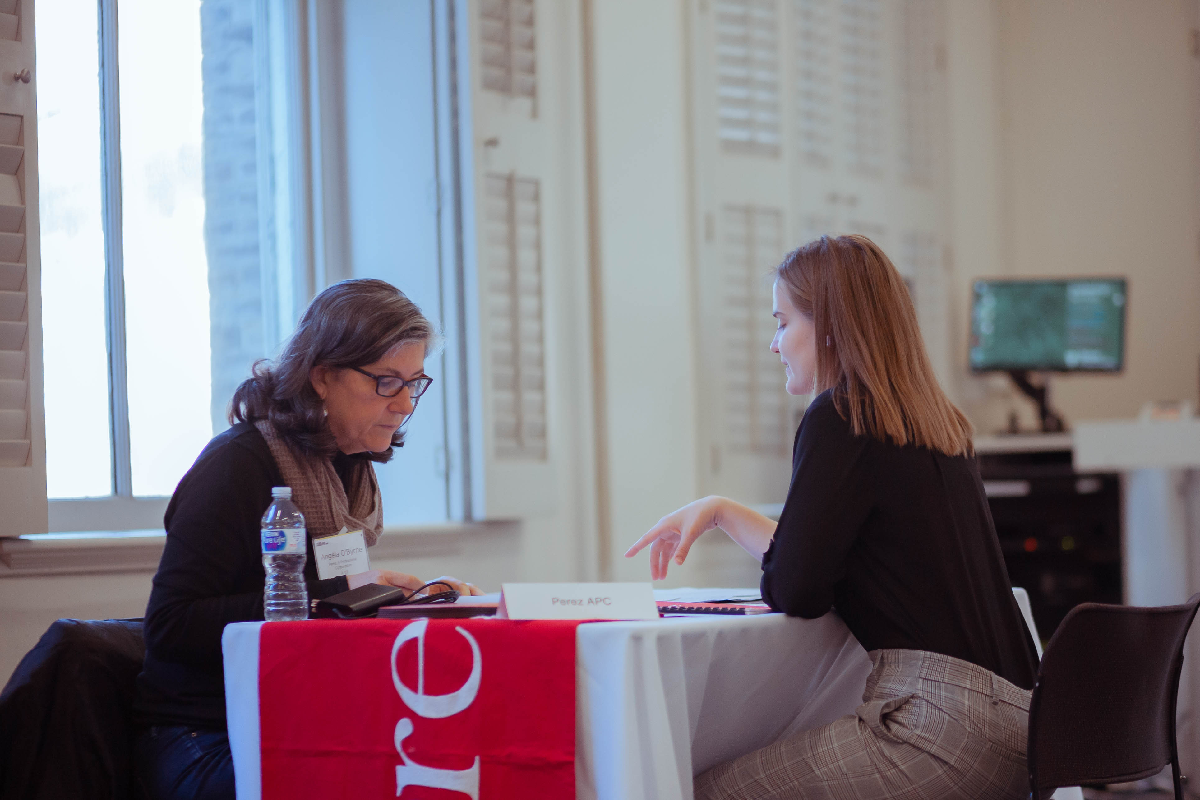 Alumni and Student sitting and speaking at a table at a Career Day Event
