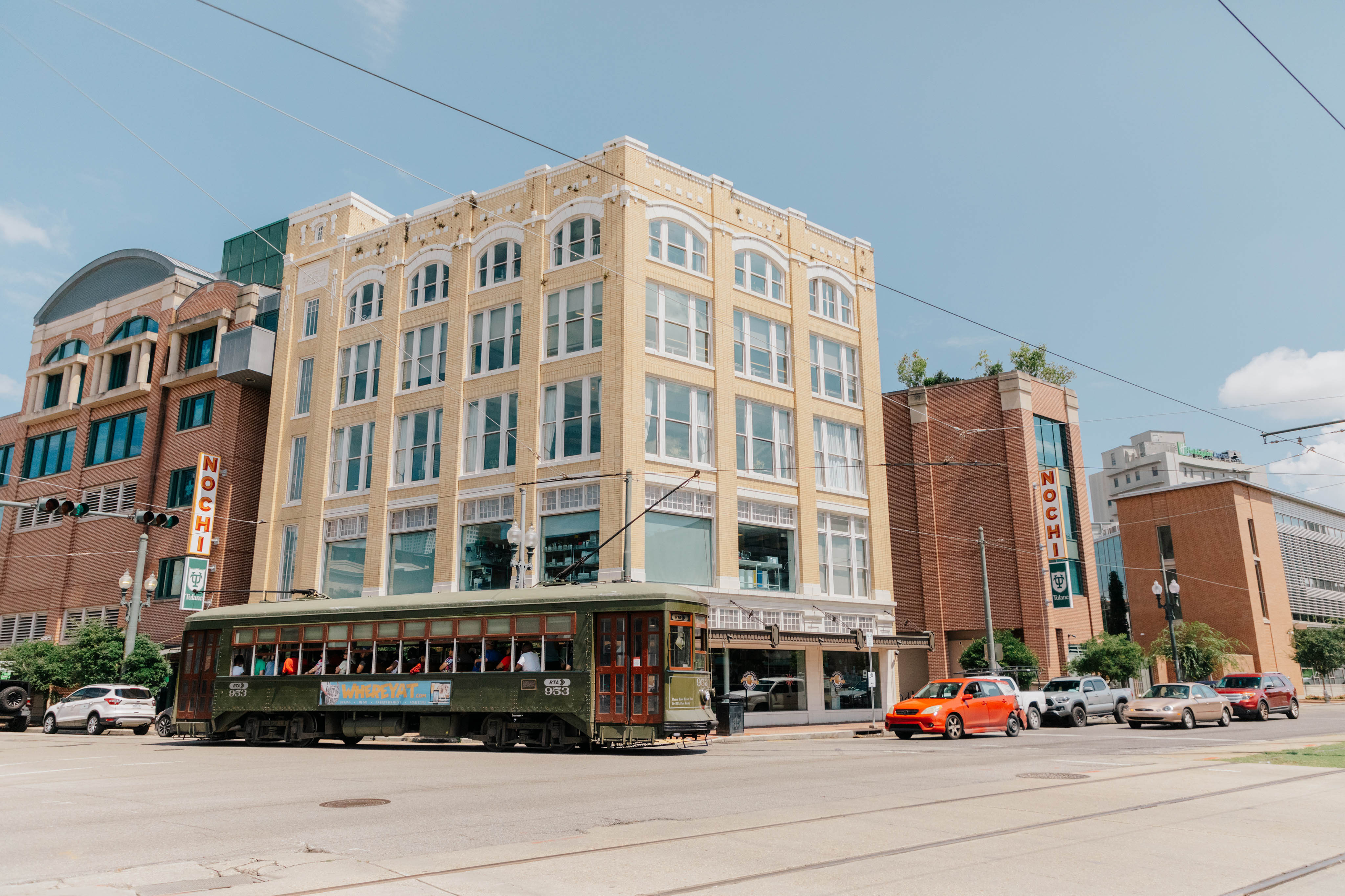 exterior of 5-story building on a corner in a downtown setting with a streetcar passing in the foreground