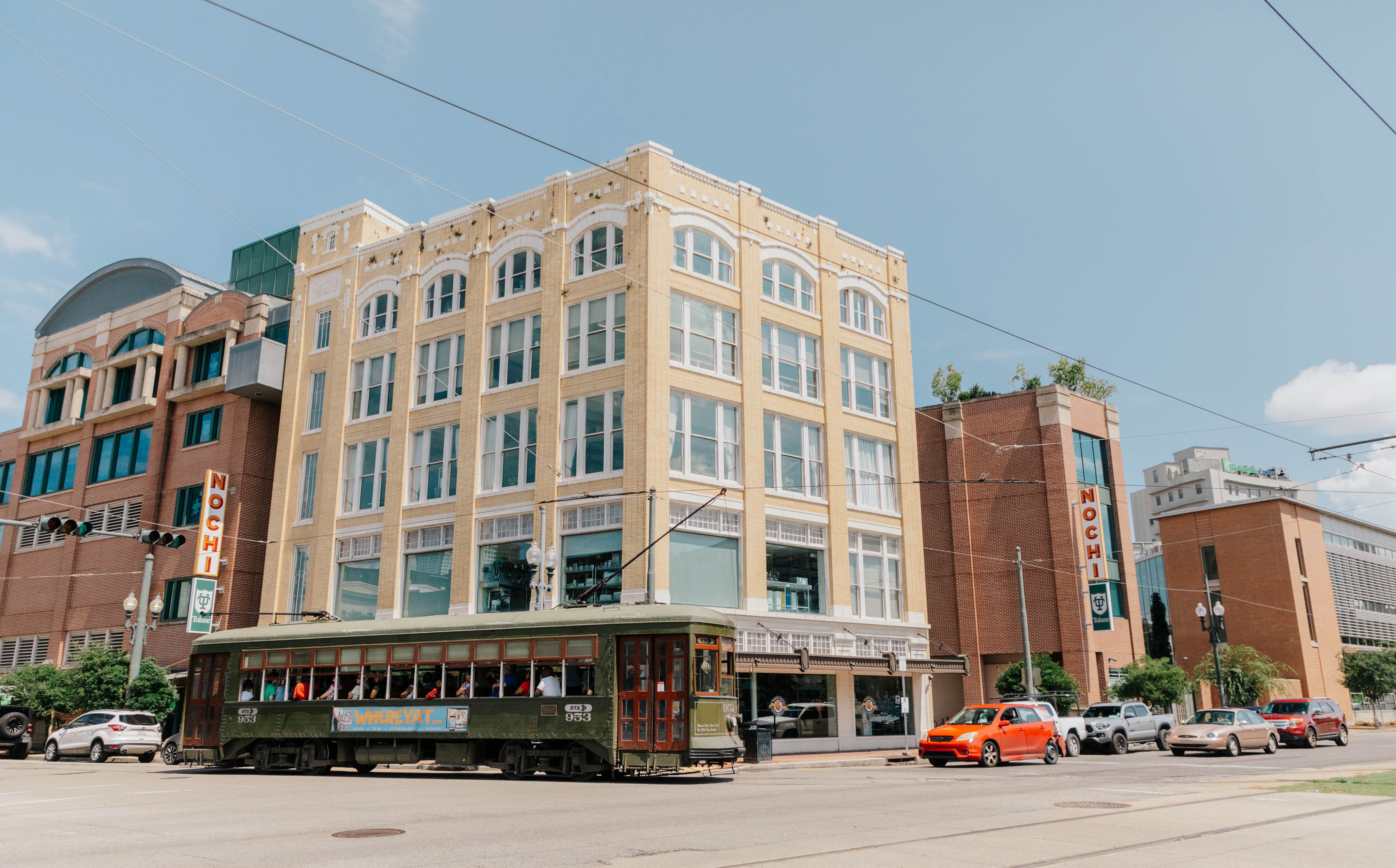 Exterior of five-story building on a corner in a downtown setting with a streetcar passing in the foreground