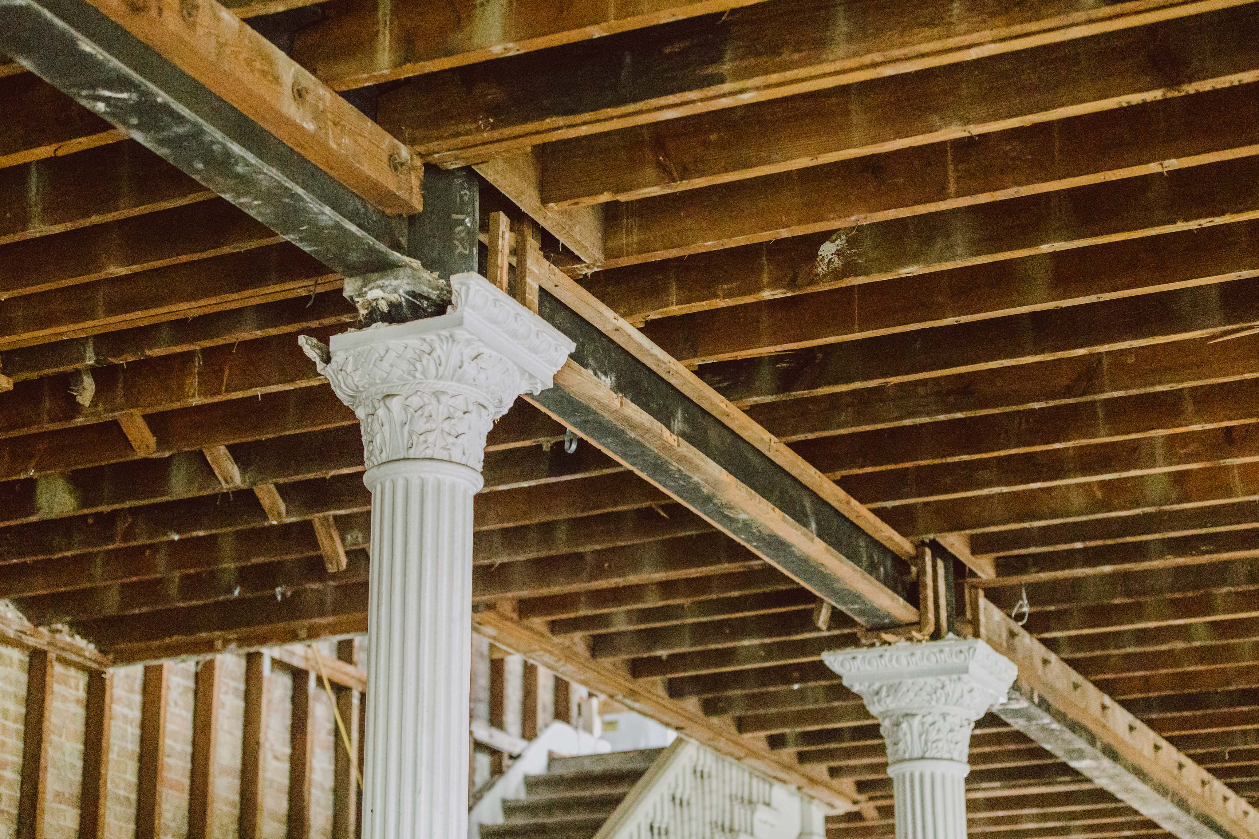 Interior view of wooden rafters and ceiling structure connecting to two columns with ornate capitals