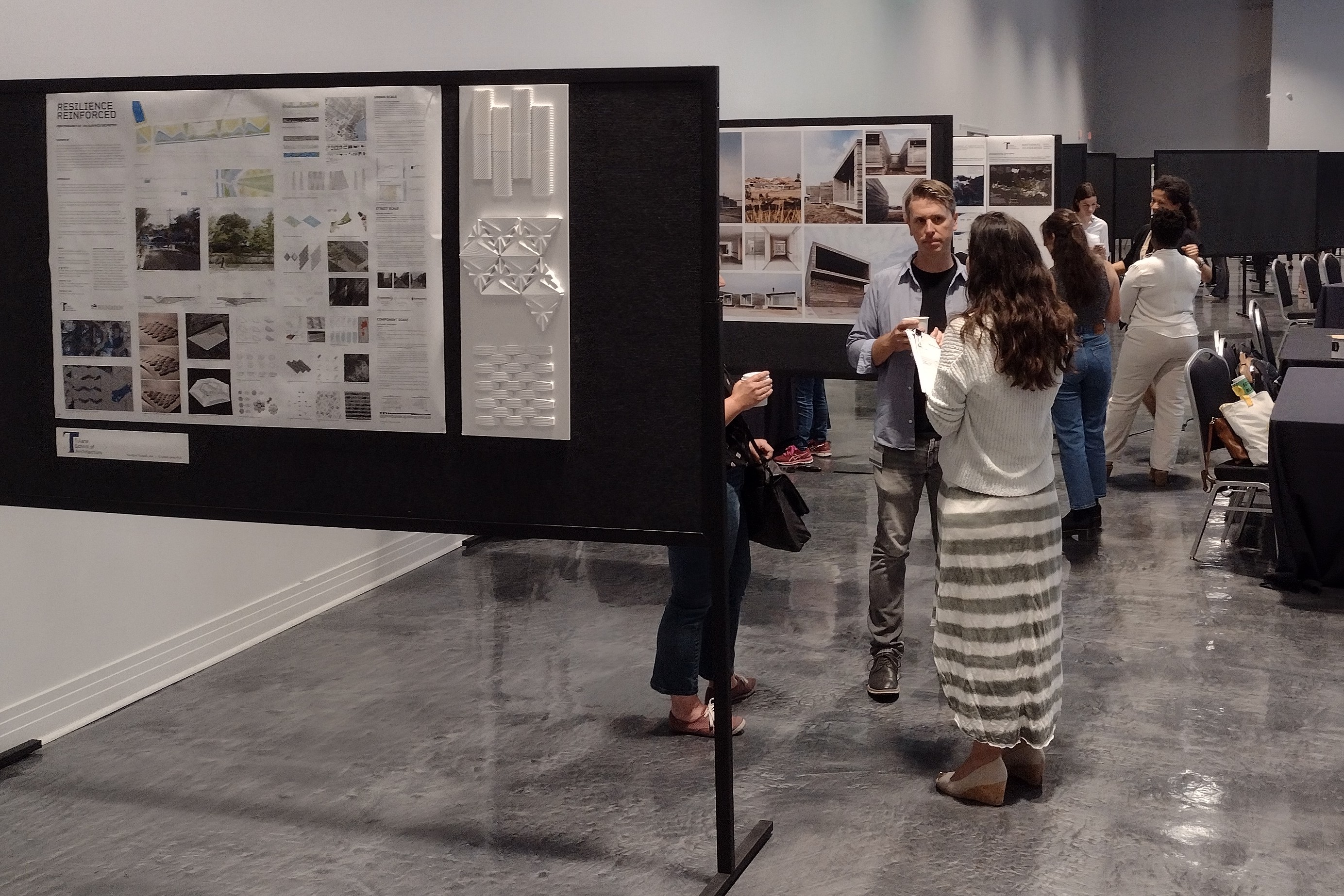 people standing next to academic research posters pinned up on boards inside a large room