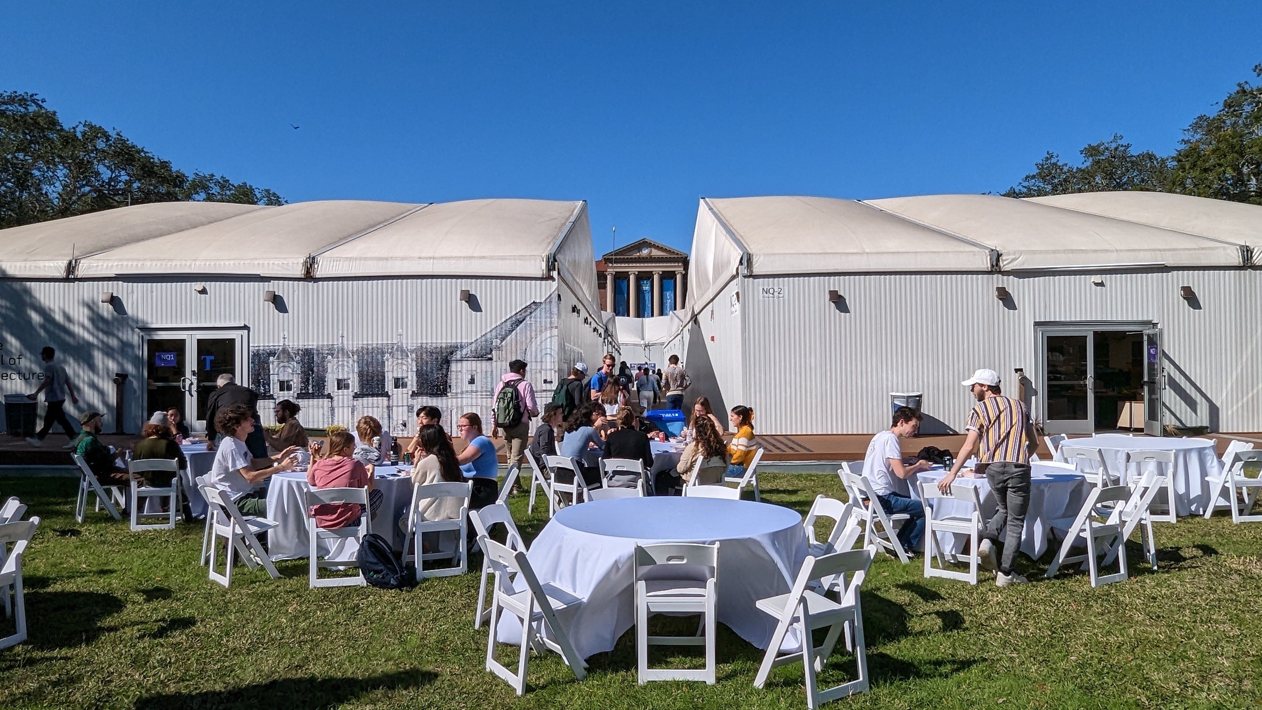 Front of Tulane School of Architecture pavillions with tables in front and people sitting and enjoying a nice day