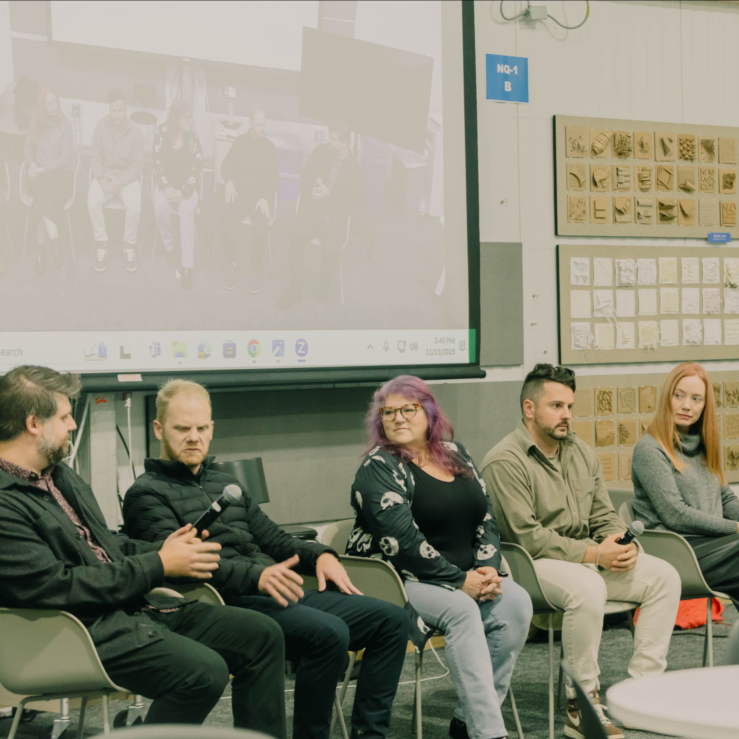 Photo of panel speaking in front of projector screen