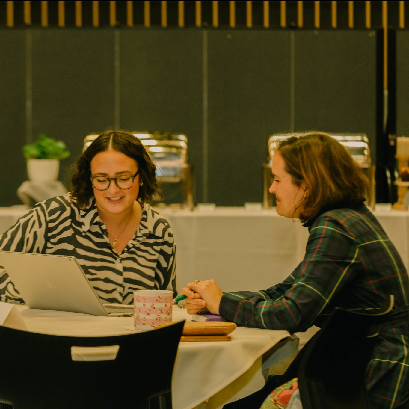 Two people having a conversation at a table with a computer between them