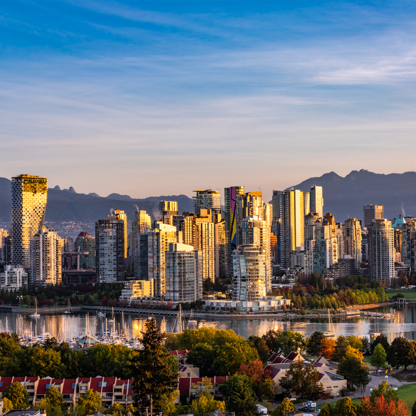Skyline of Vancouver, British Columbia, Canada, with a mountain range behind downtown's tall buildings and water front properties.