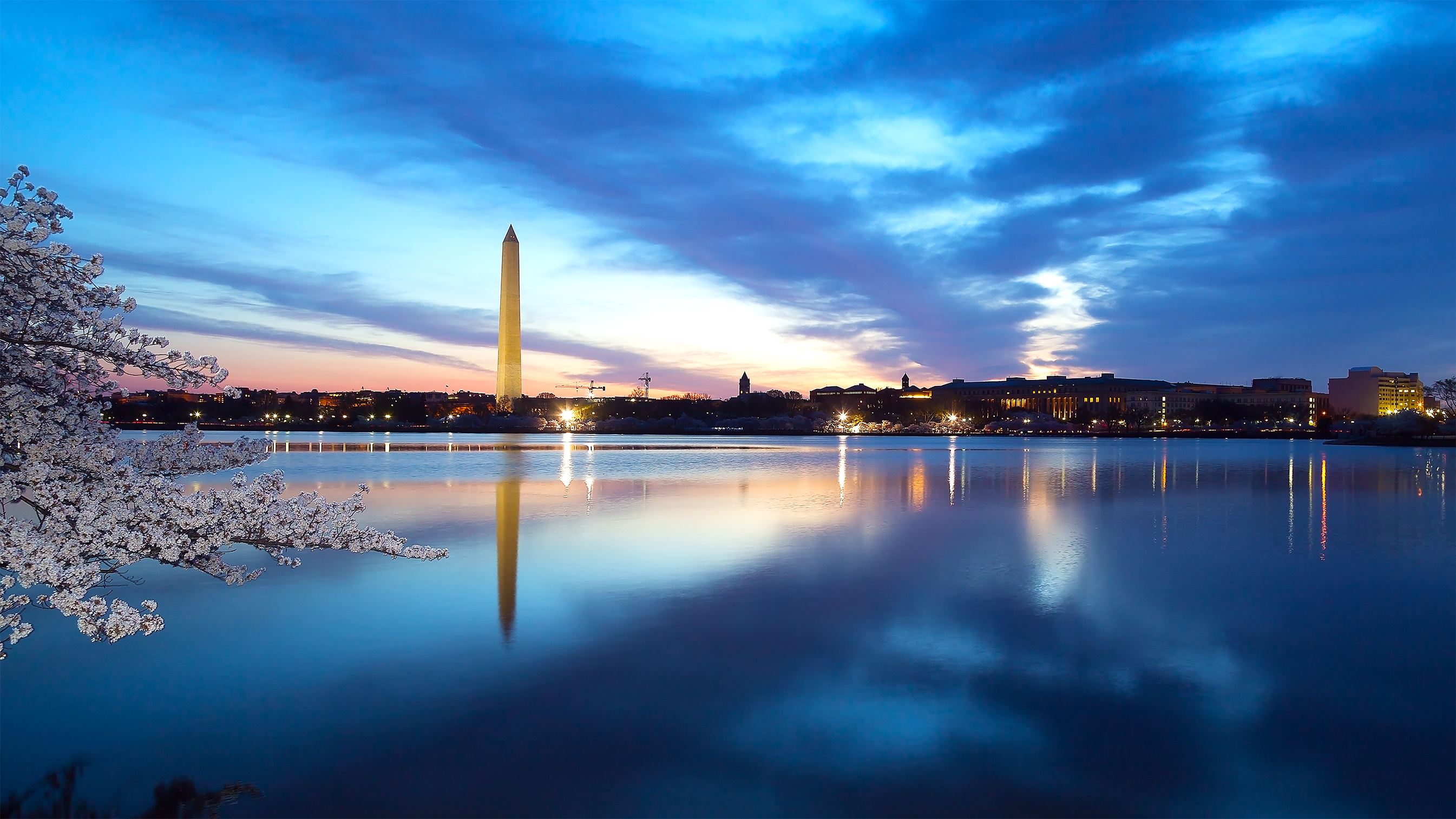 Skyline of Washington, D.C., at late sunset with the Potomac River in the foreground and Washington Memorial in the left background.
