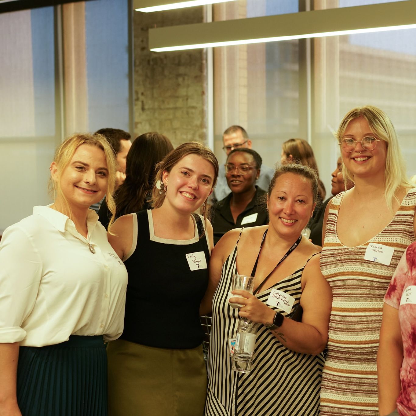 Group of four femme presenting people posing together for a photo at an event 