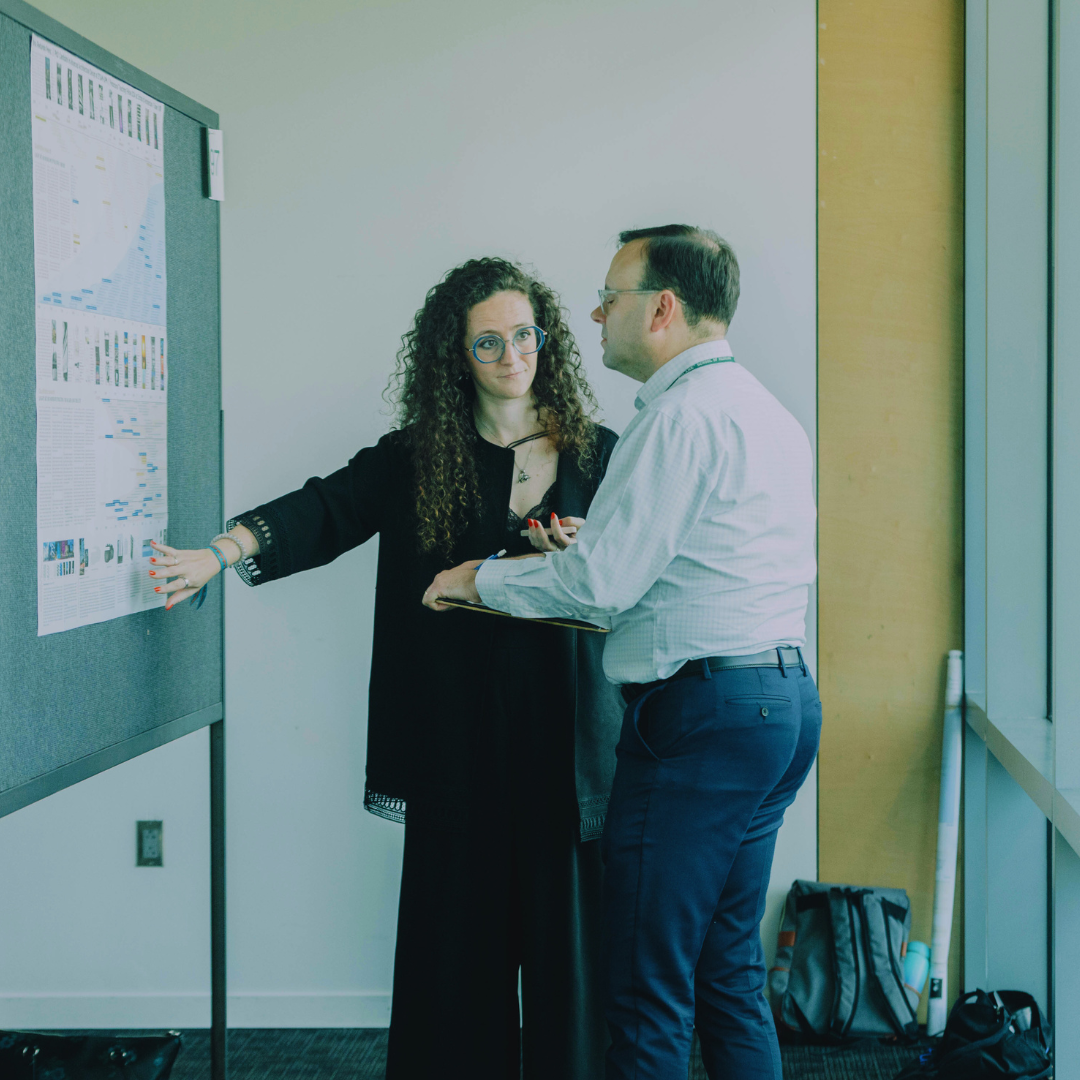 Faculty Maria Redondo Perez talks to a person looking at her poster presentation.