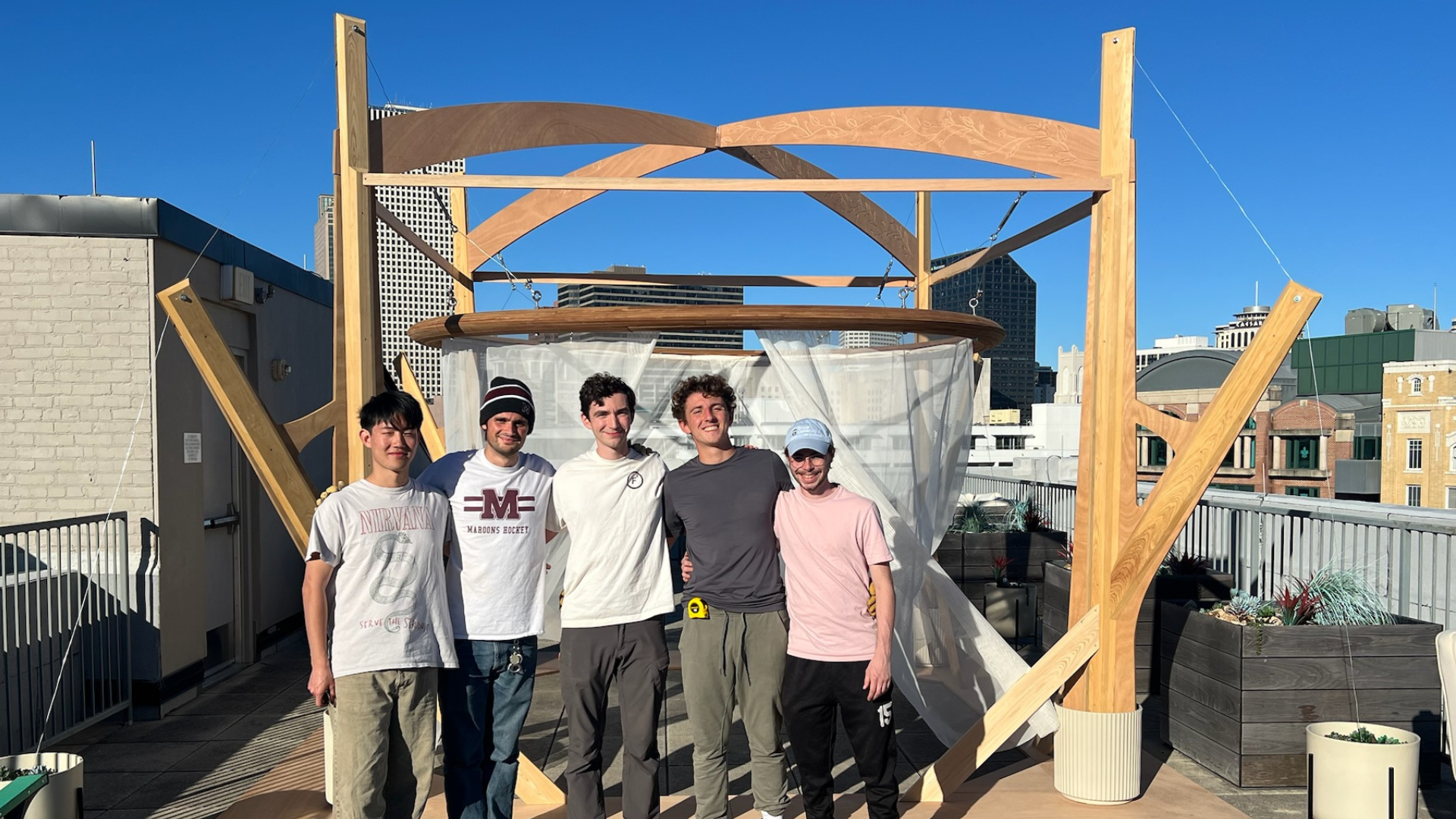 Sukkah 16 students stand in front of their rooftop design-build sukkah.