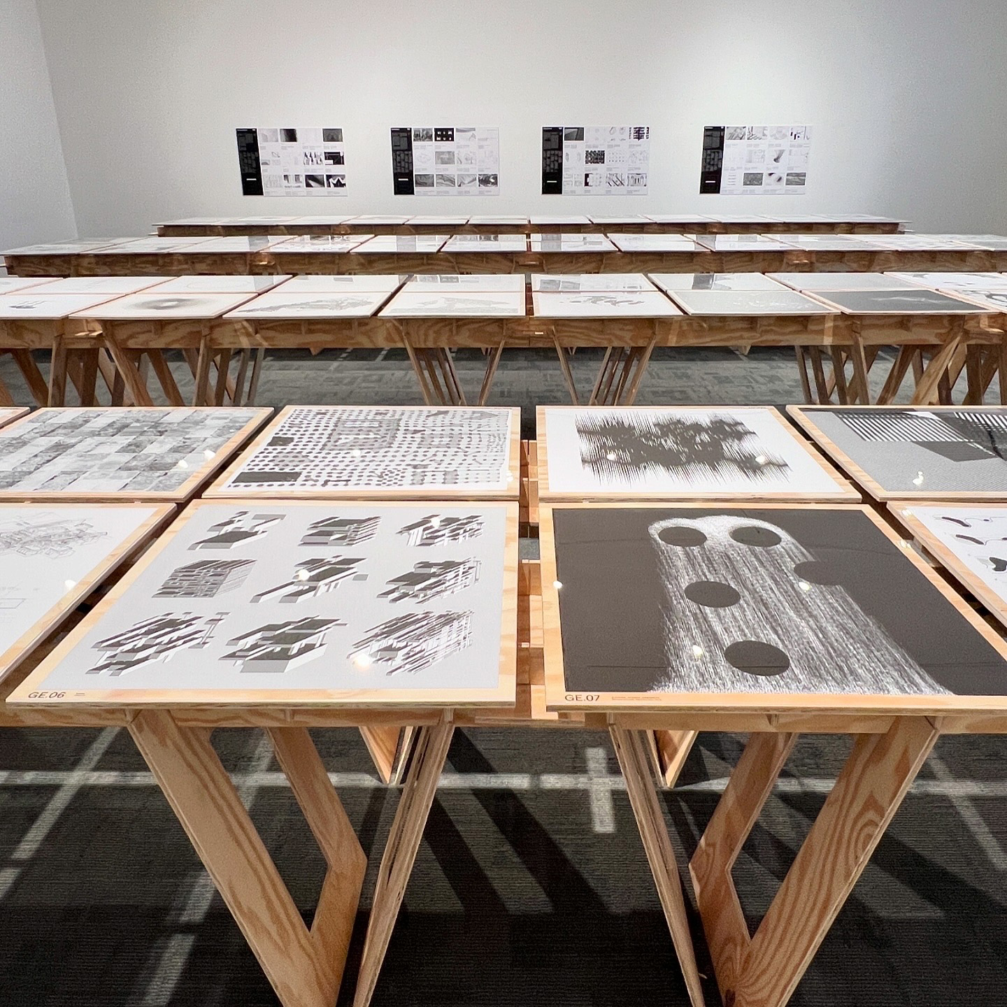 Computational drawings on exhibit tables in a gallery space.
