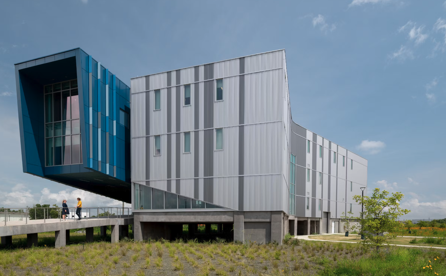 Exterior view of LUMCON Blue Works, a large four-story industrial style building with metal siding and large windows on the left side.