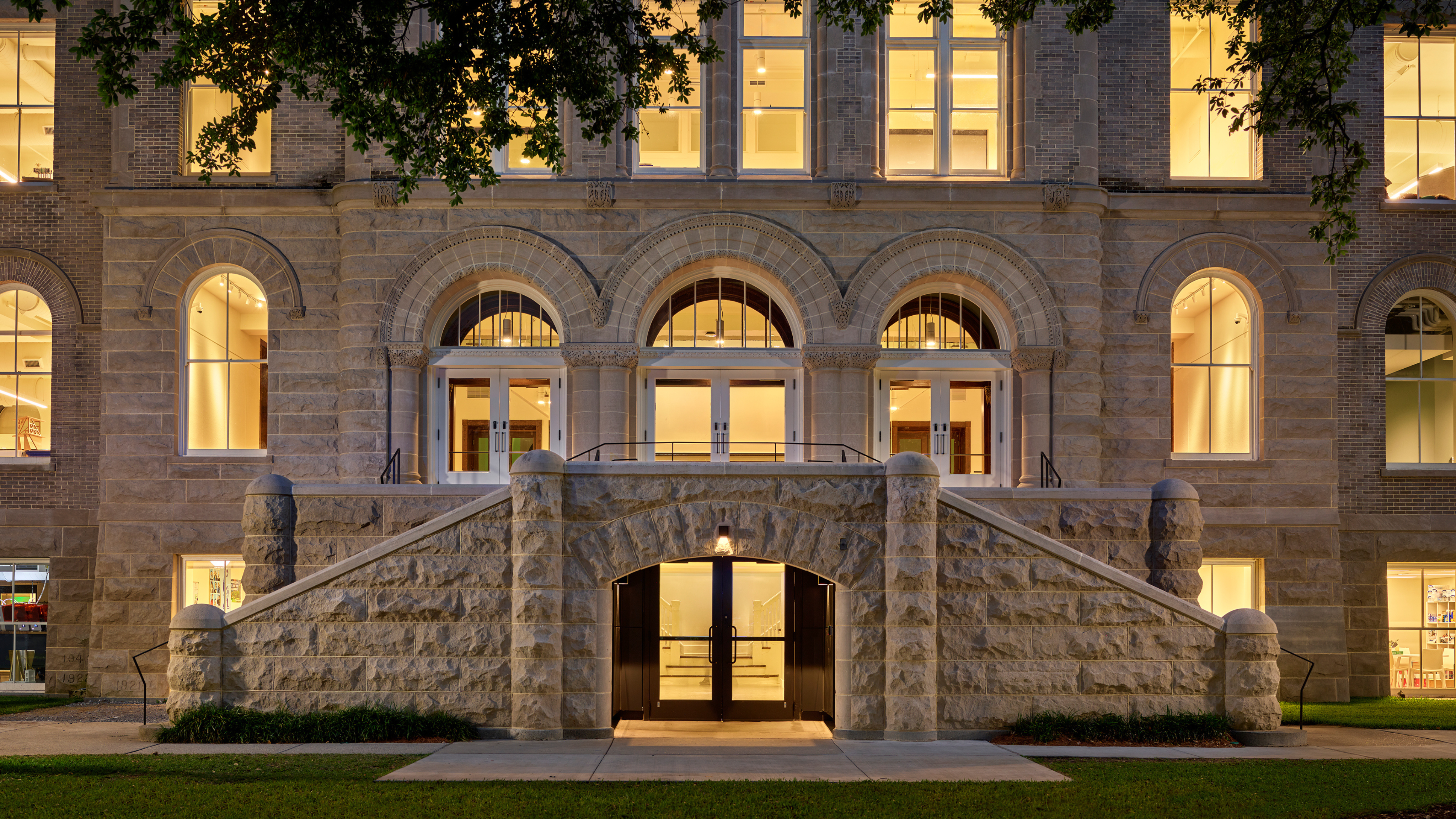 Front facade of historic Richardson Memorial Hall, looking directly at the first three floors with lights on at night.