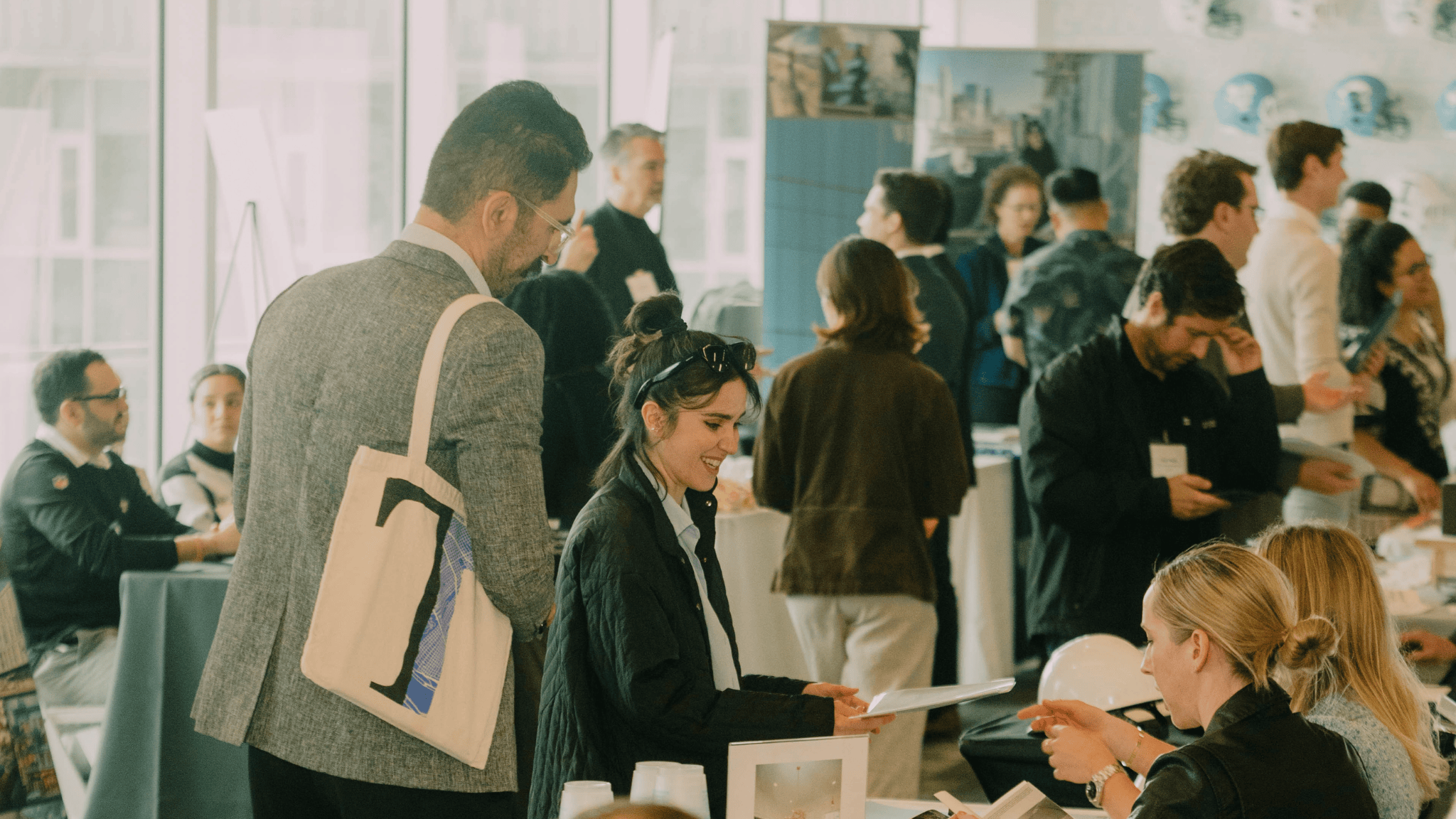 A large room hosting a career fair with rows of employer tables and students walking through the rows.