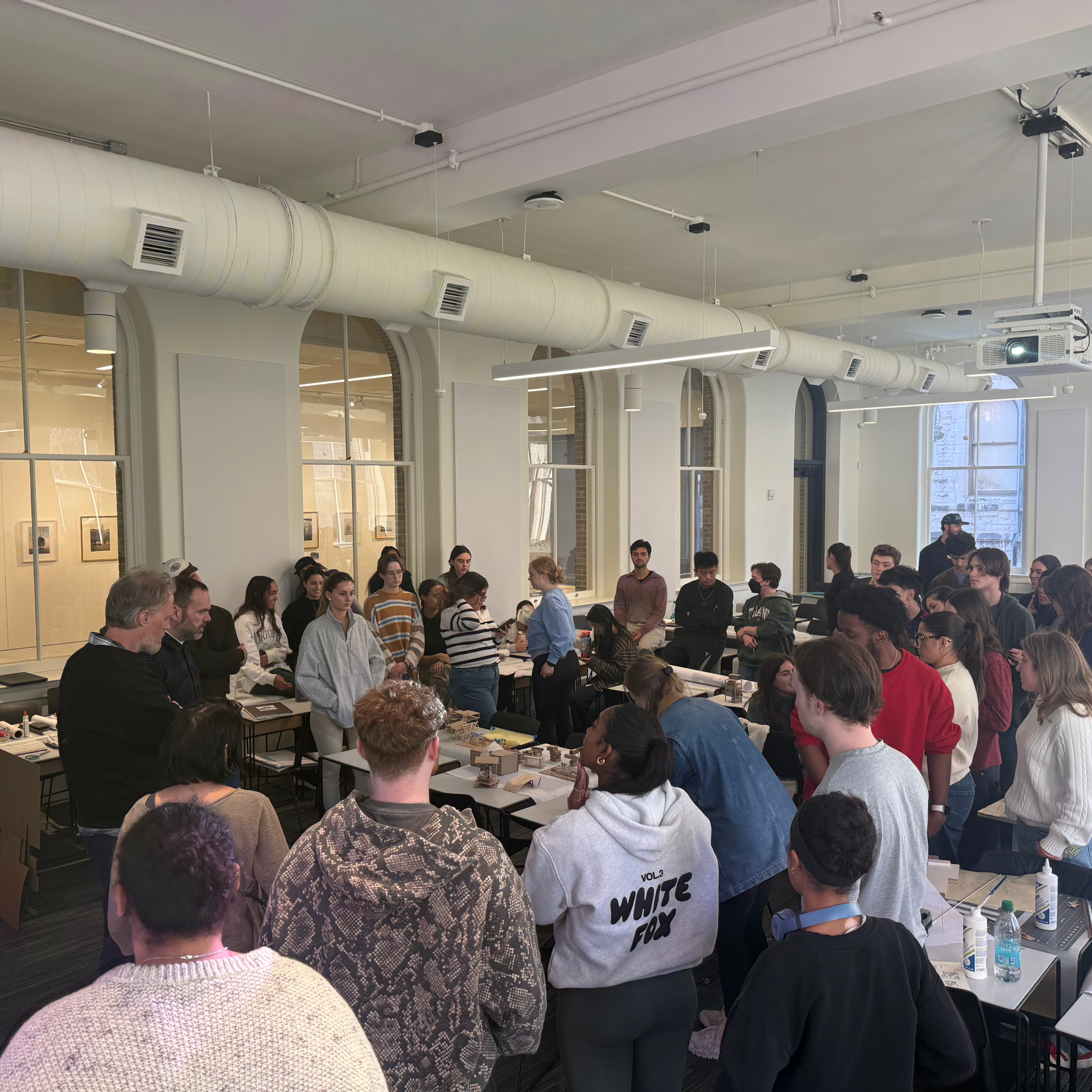 Students surround workshop leaders and architectural models 