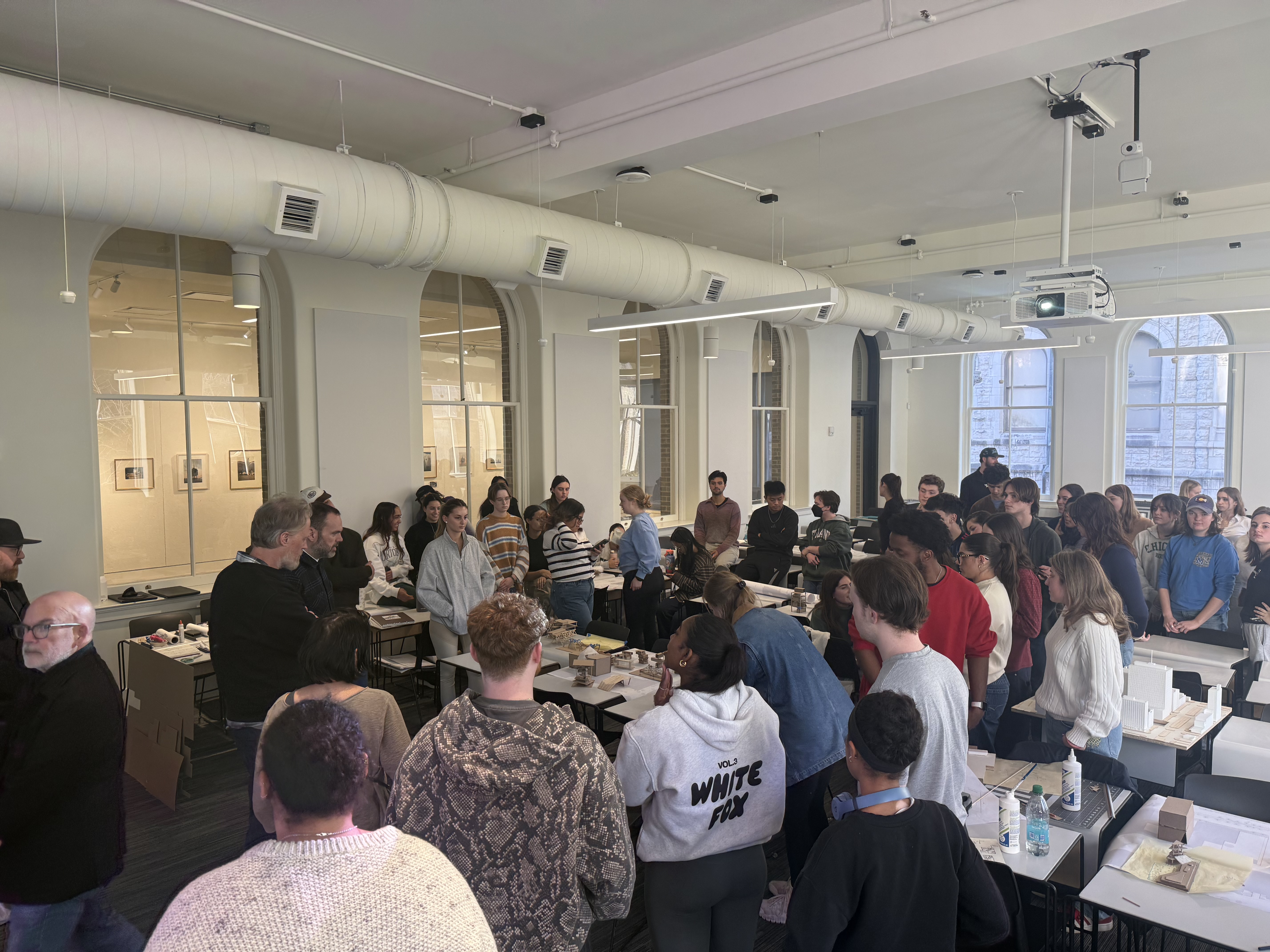 Students surround workshop leaders and architectural models. 