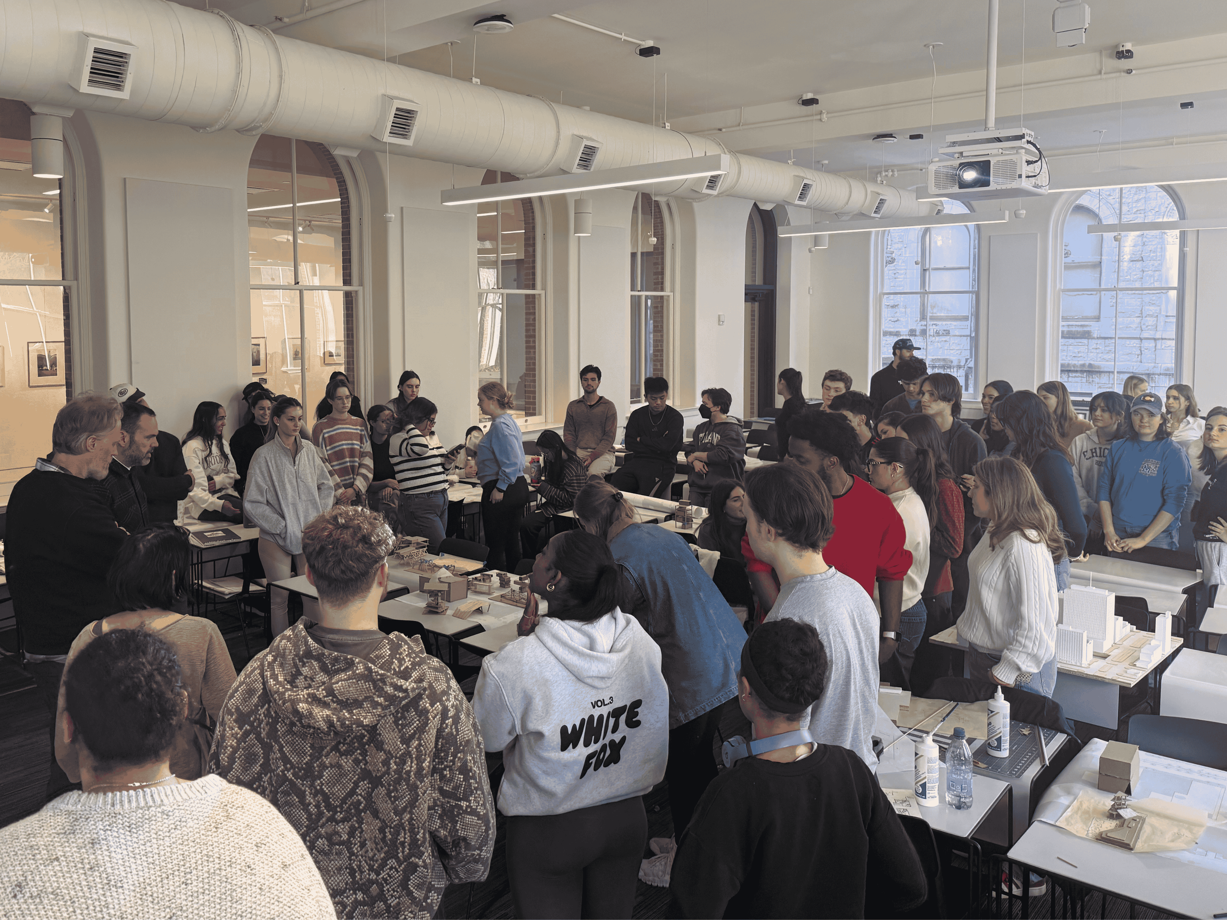 Students surround workshop leaders and architectural models.