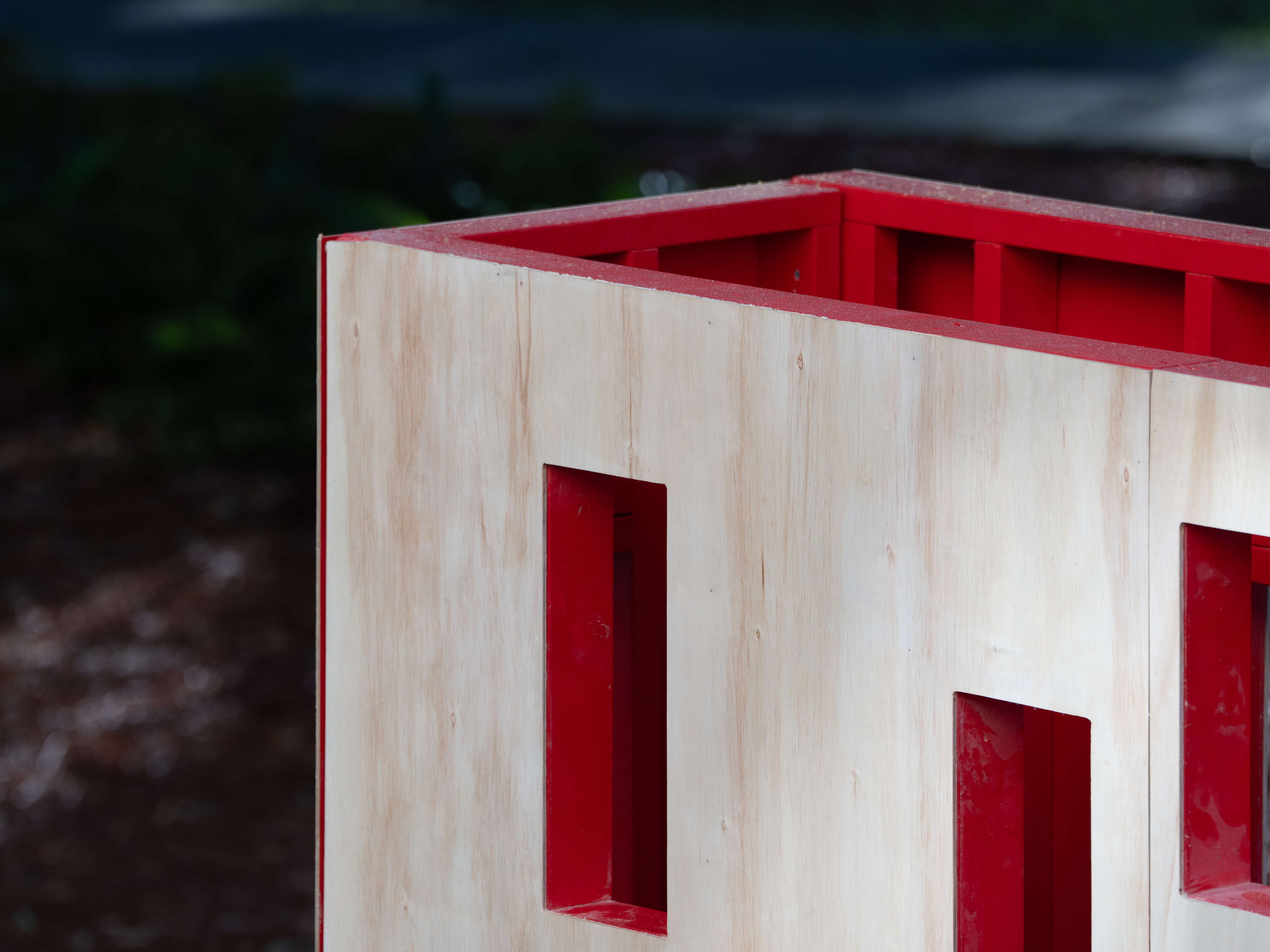 Close-up of Architecture students' project, showing the top corner of a hollow wooden structure with windows exposing a red inside