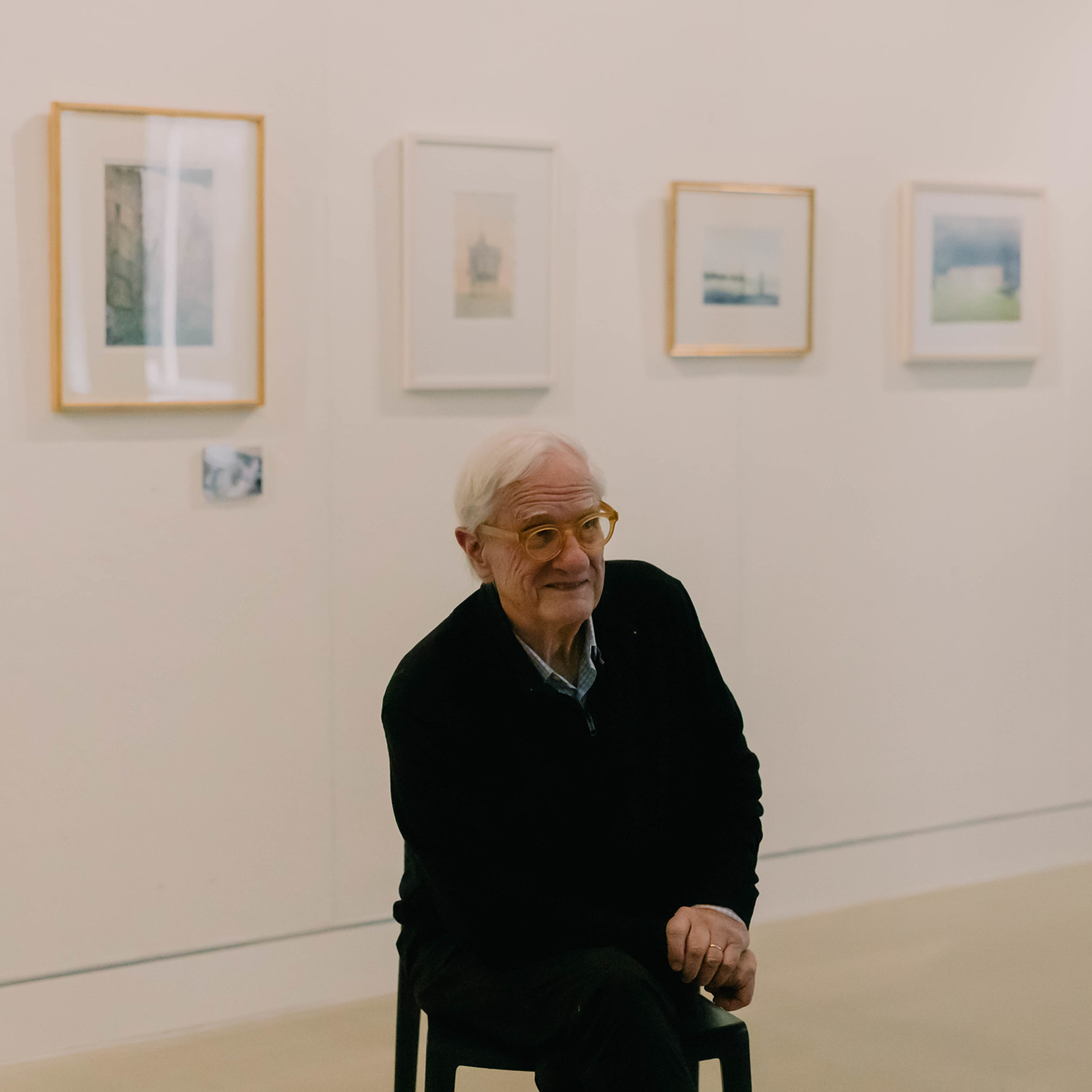 Errol Barron sitting in front of photographs on a white wall