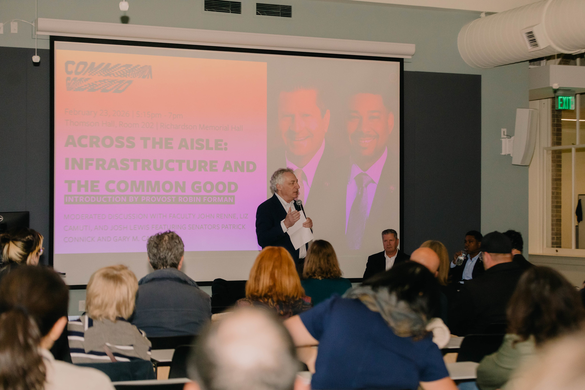 Robin Forman introduces senators in a large room in RMH