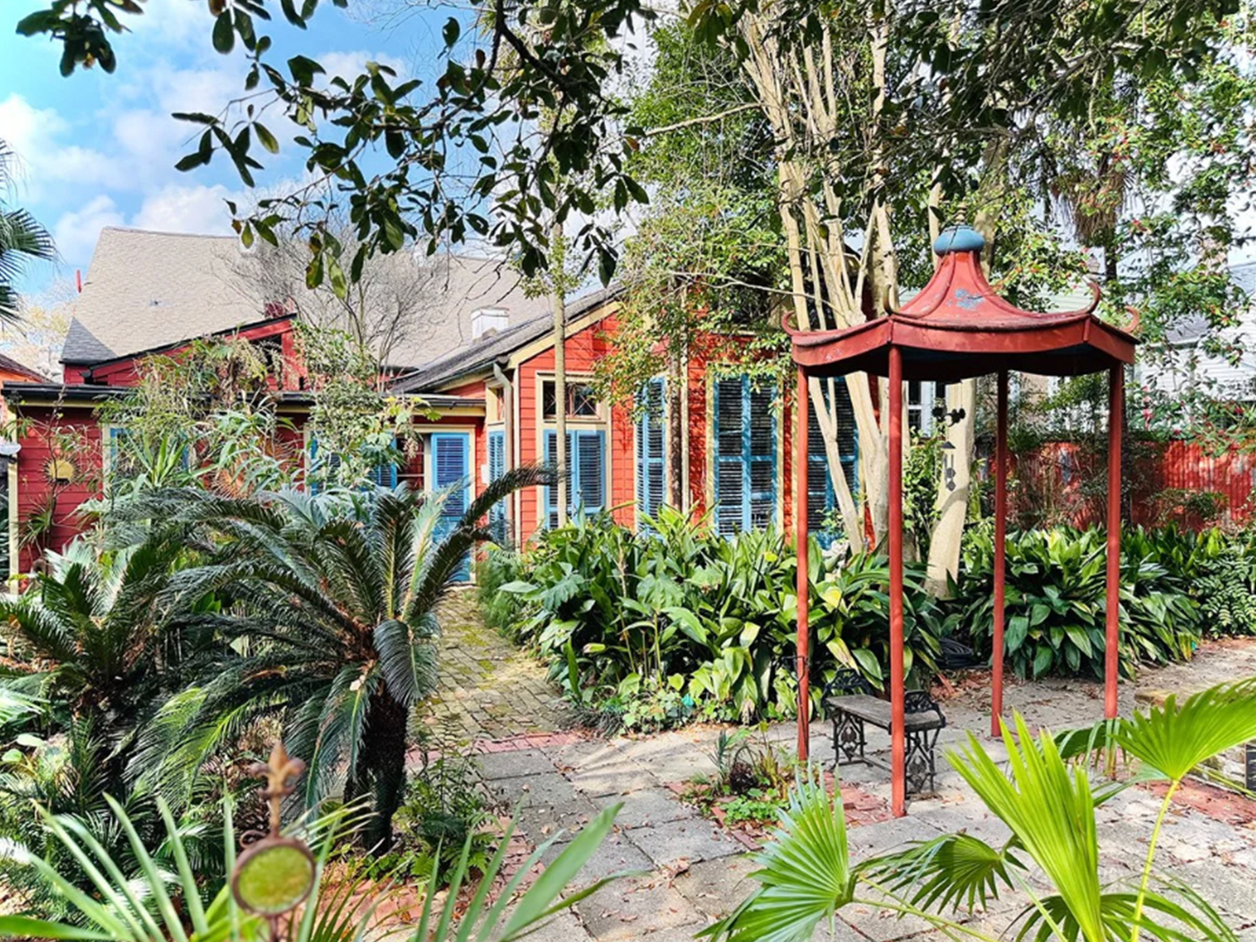 The back of Gene Cizek's house and backyard, with a cobblestone path and an orange gazebo that matches the house's color.