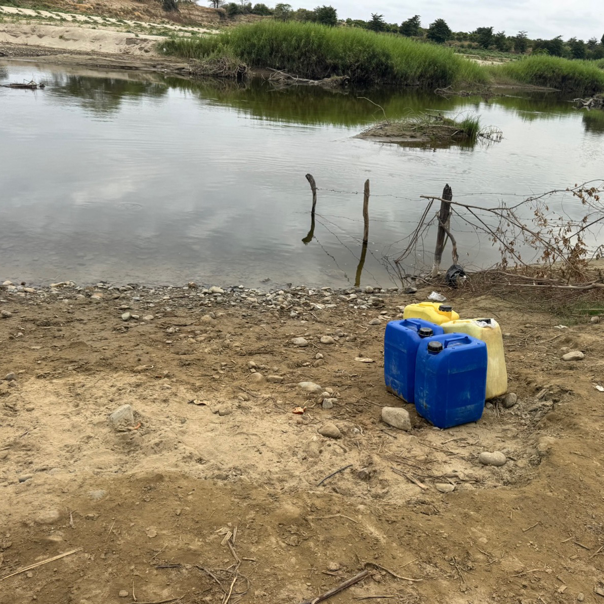 photo of potable water jugs sitting beside a body of water