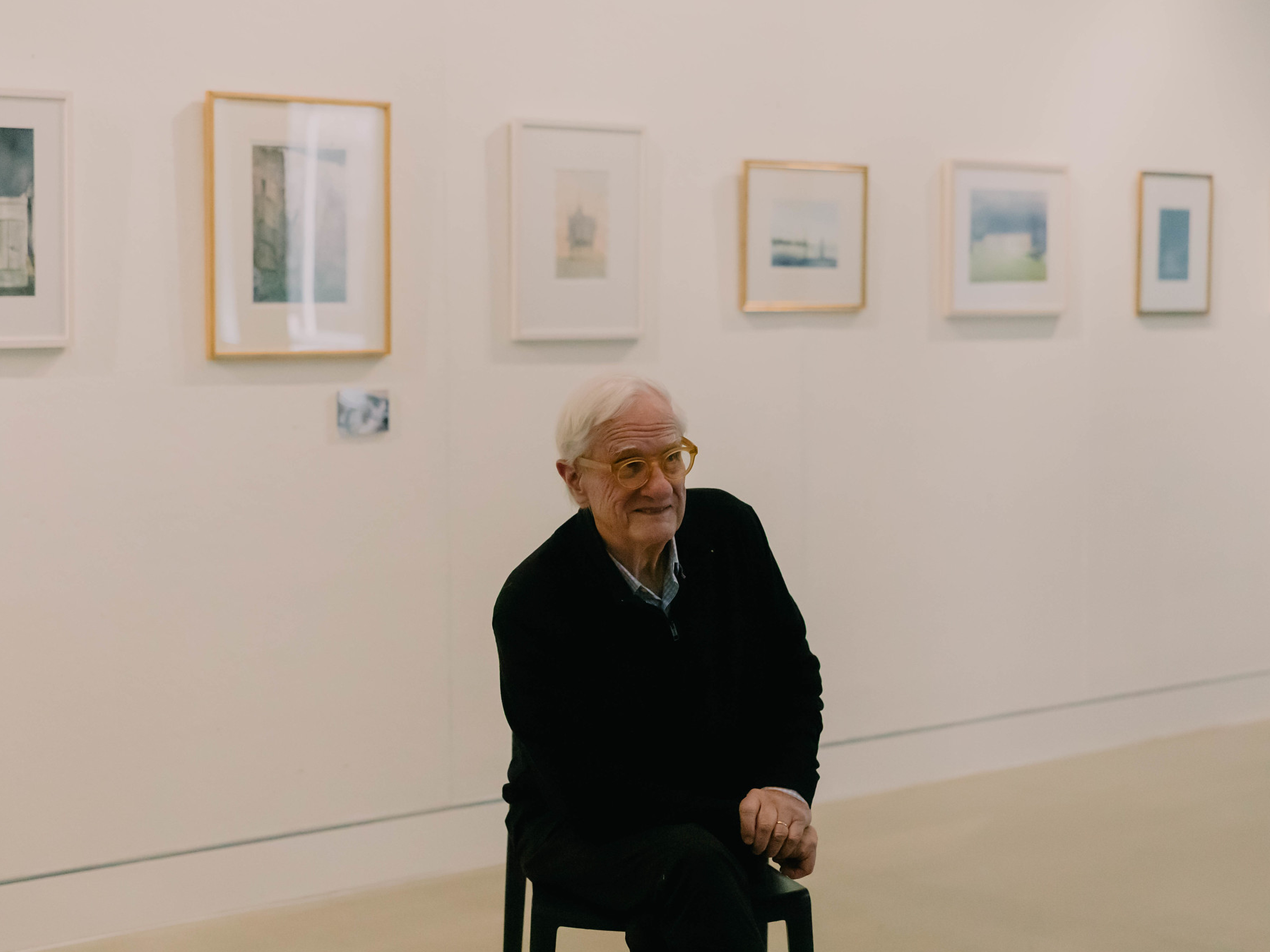 Errol Barron sitting in front of hanging photographs