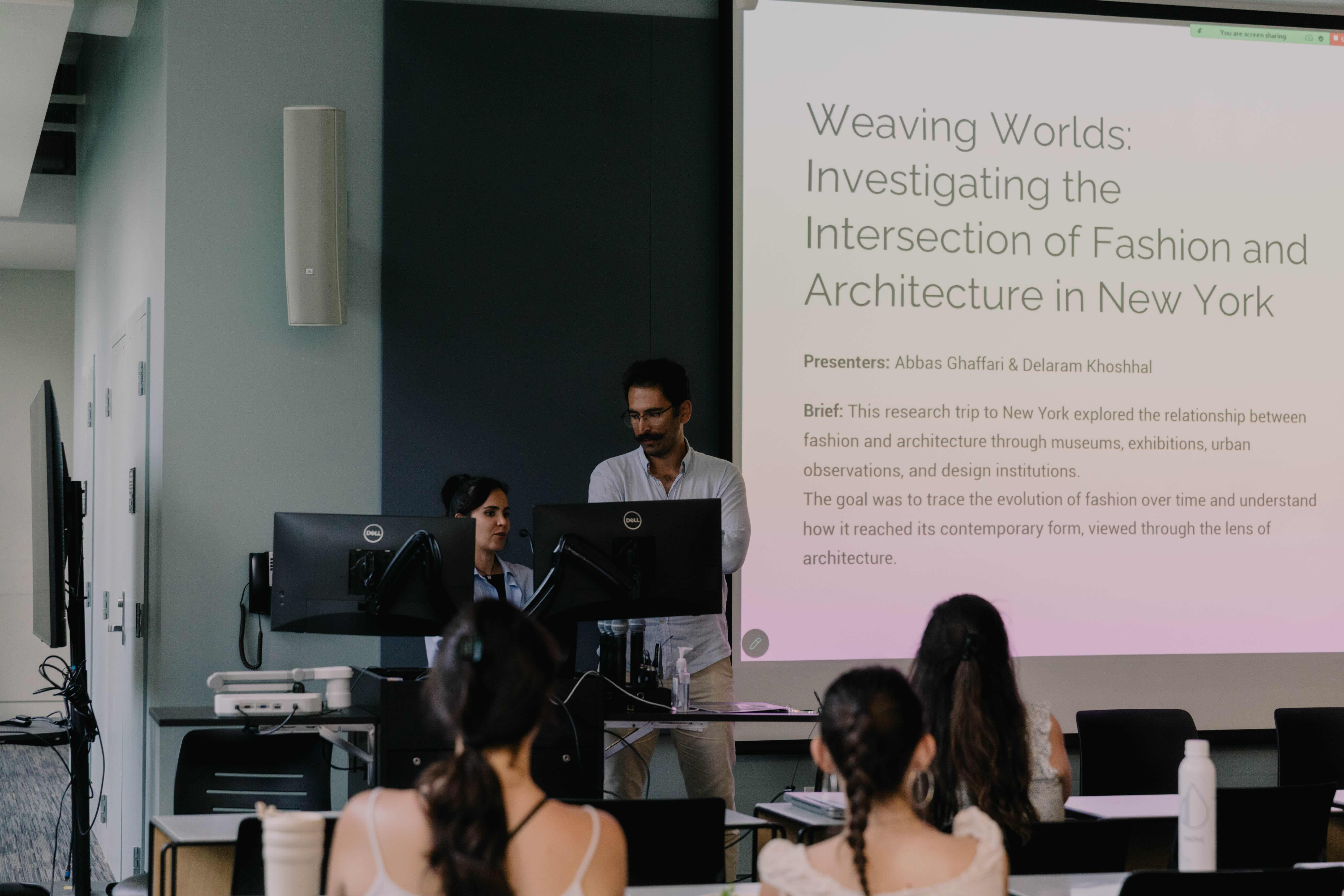 two students present in front of a powerpoint