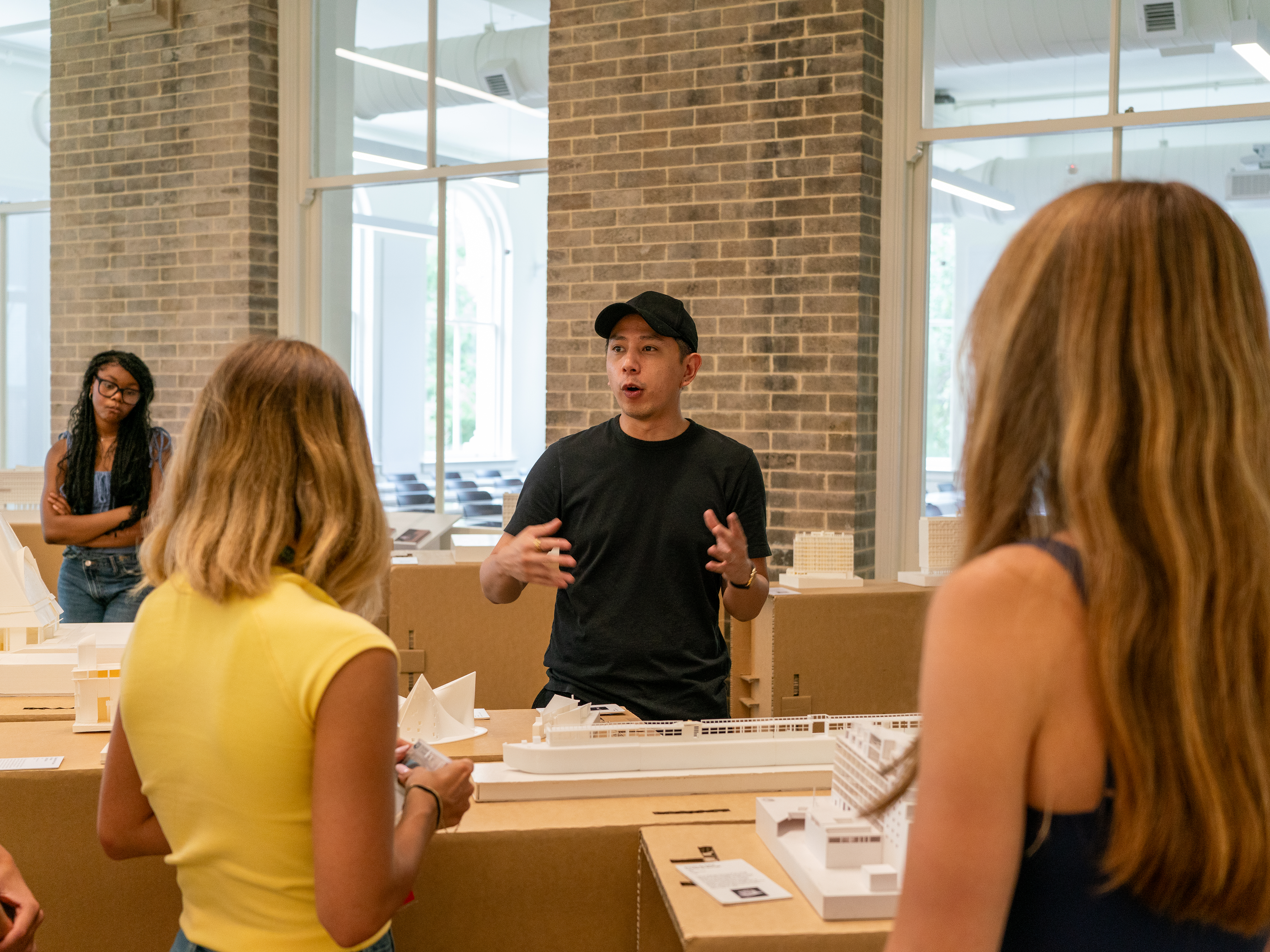 Presenter lecturing in front of model with students listening