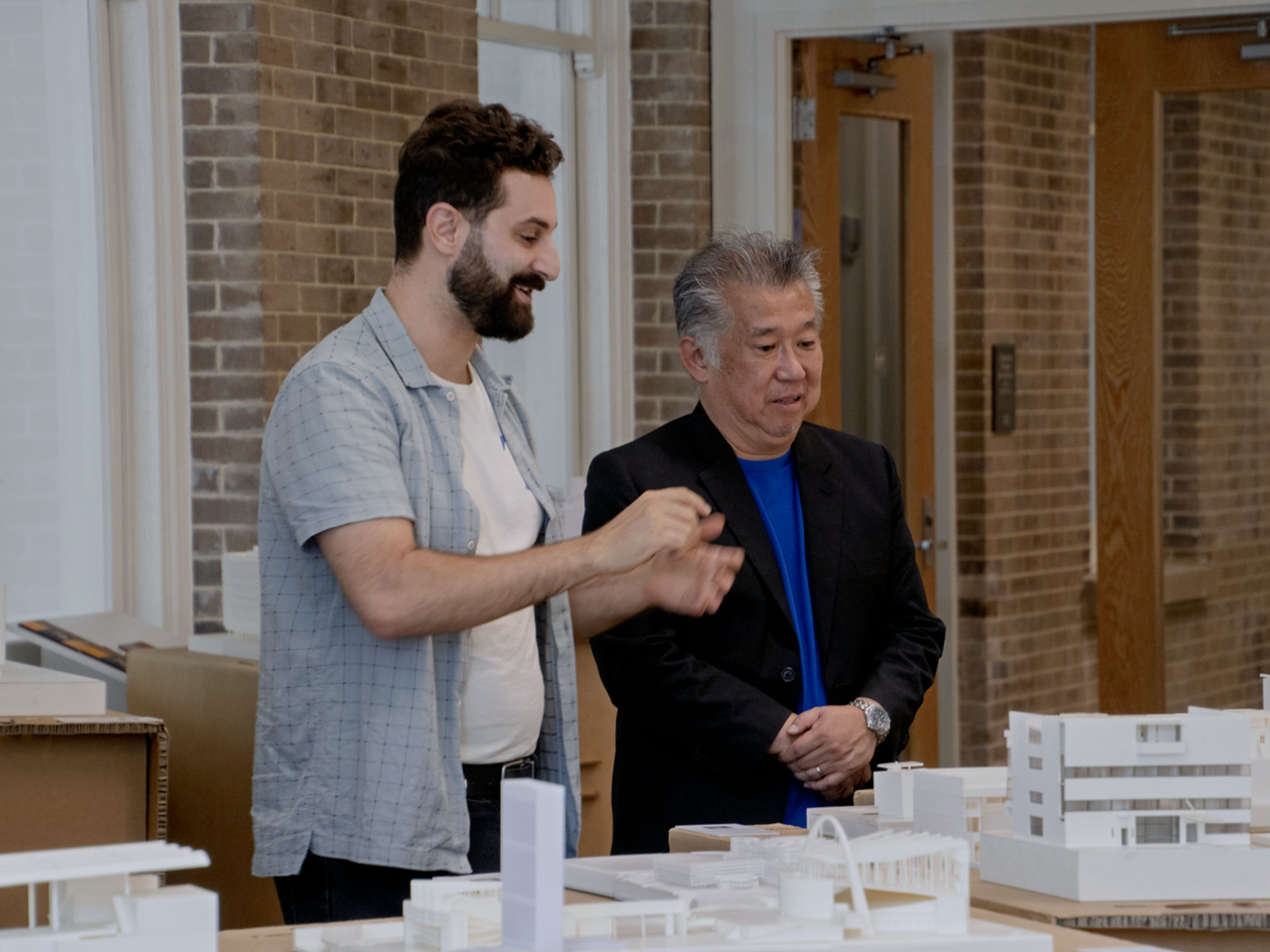 Two people standing in front of and discussing models