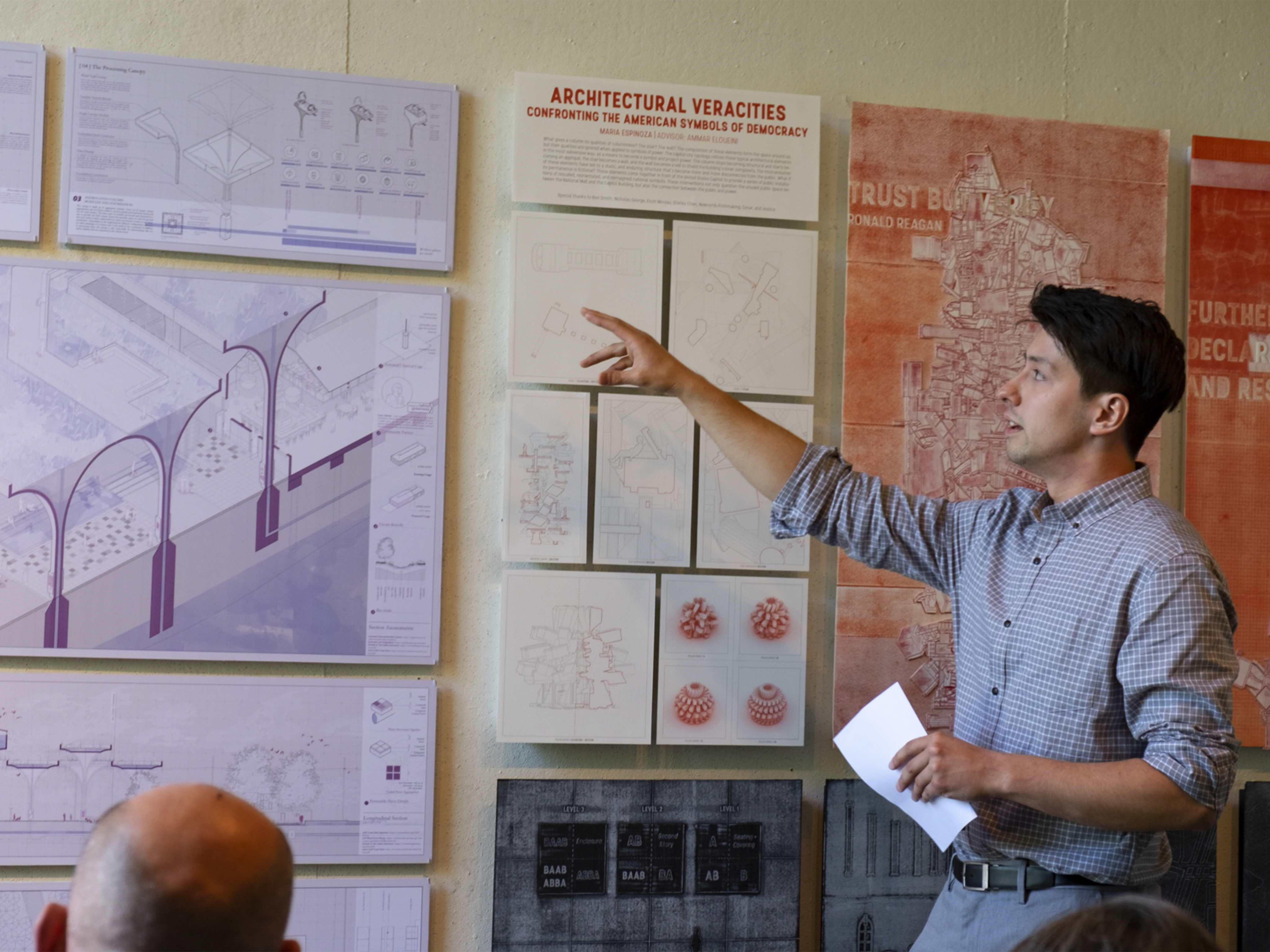 Presenter in blue shirt pointing at images on presentation board