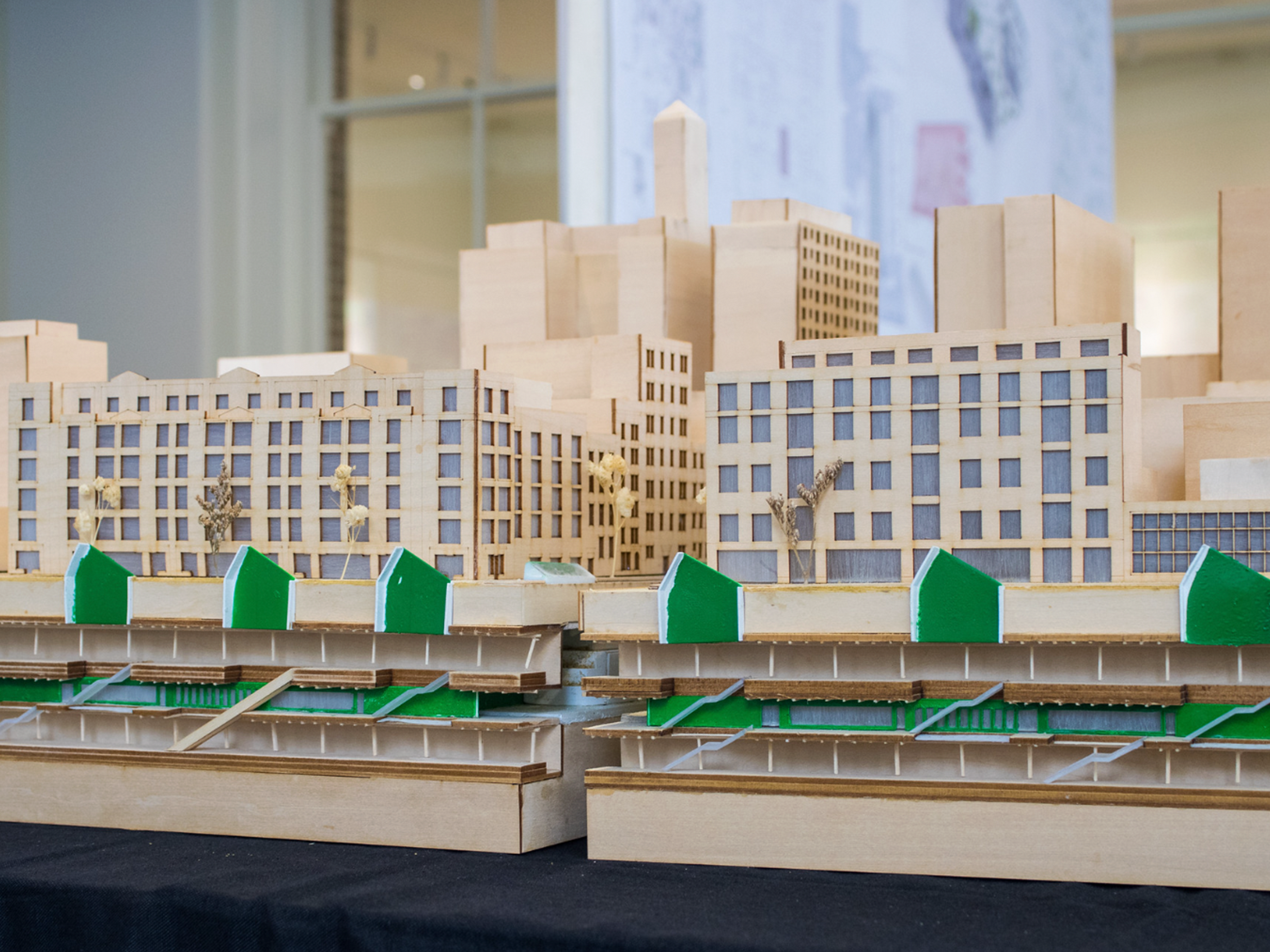 Wooden scaled model of buildings with green accents and miniature trees