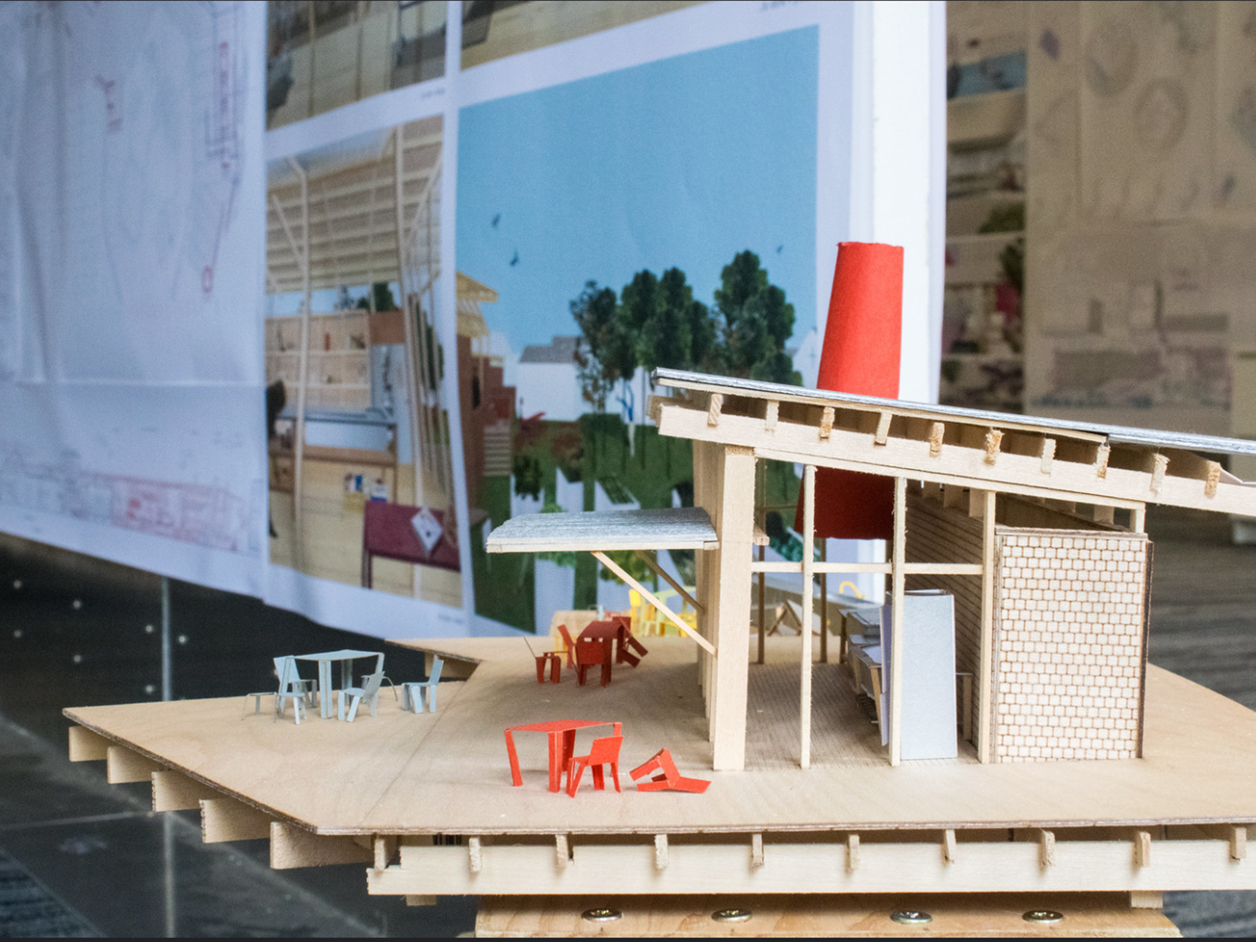 Wooden scaled model of building with slanted roof, presentation board behind it