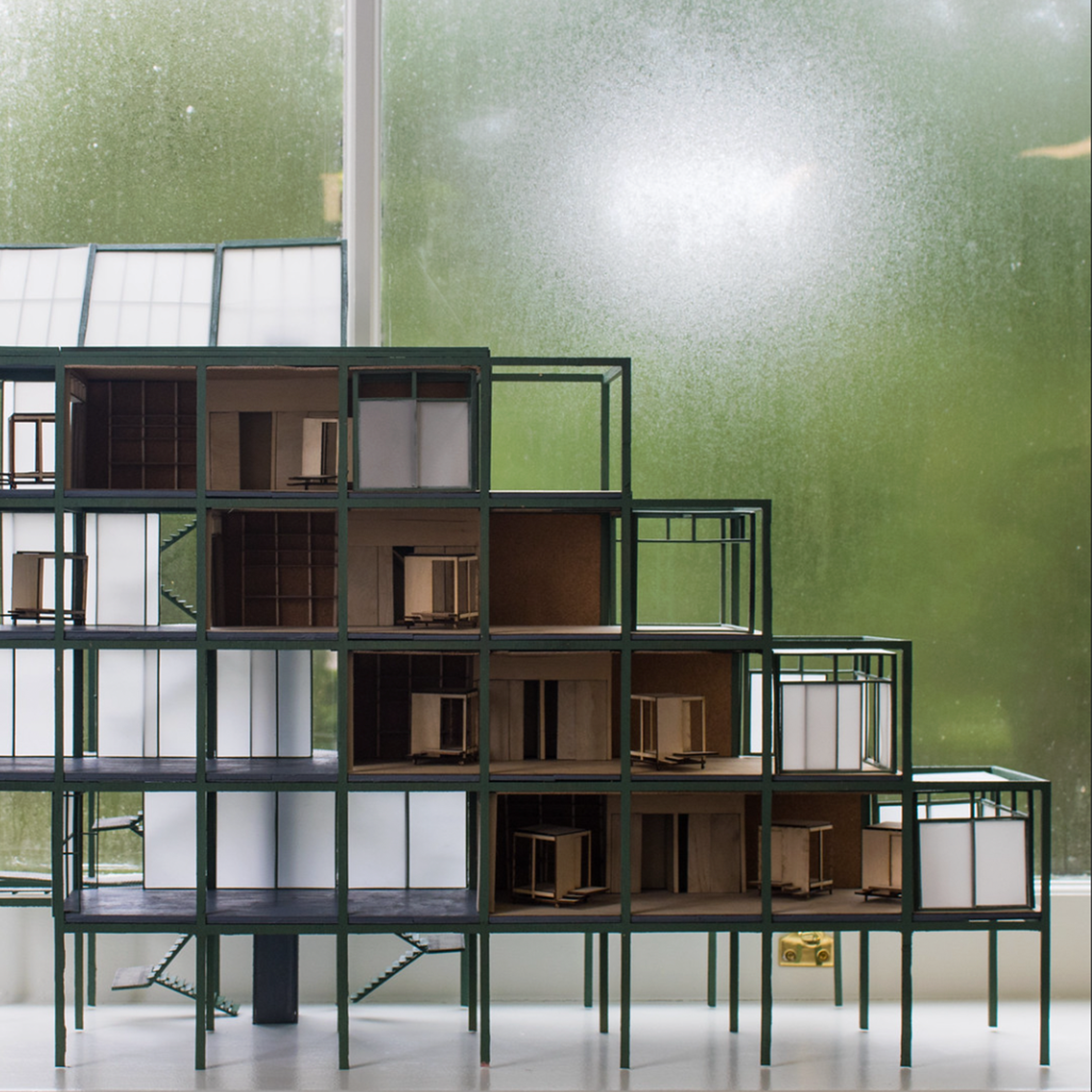 Close-up of building model with a terraced design, against a green background