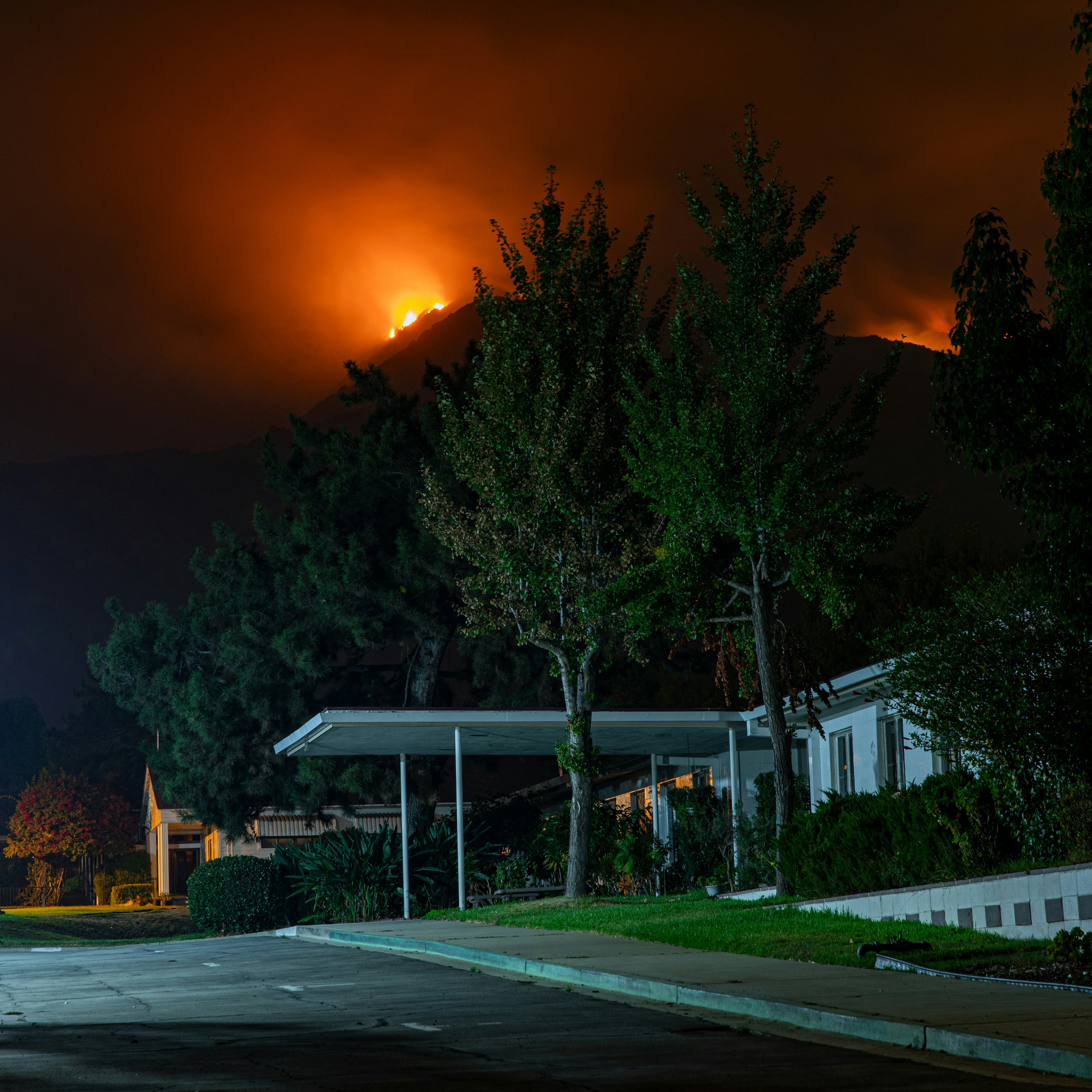 photo of Pacific Pallisades fire burning with an intact home in the foreground 