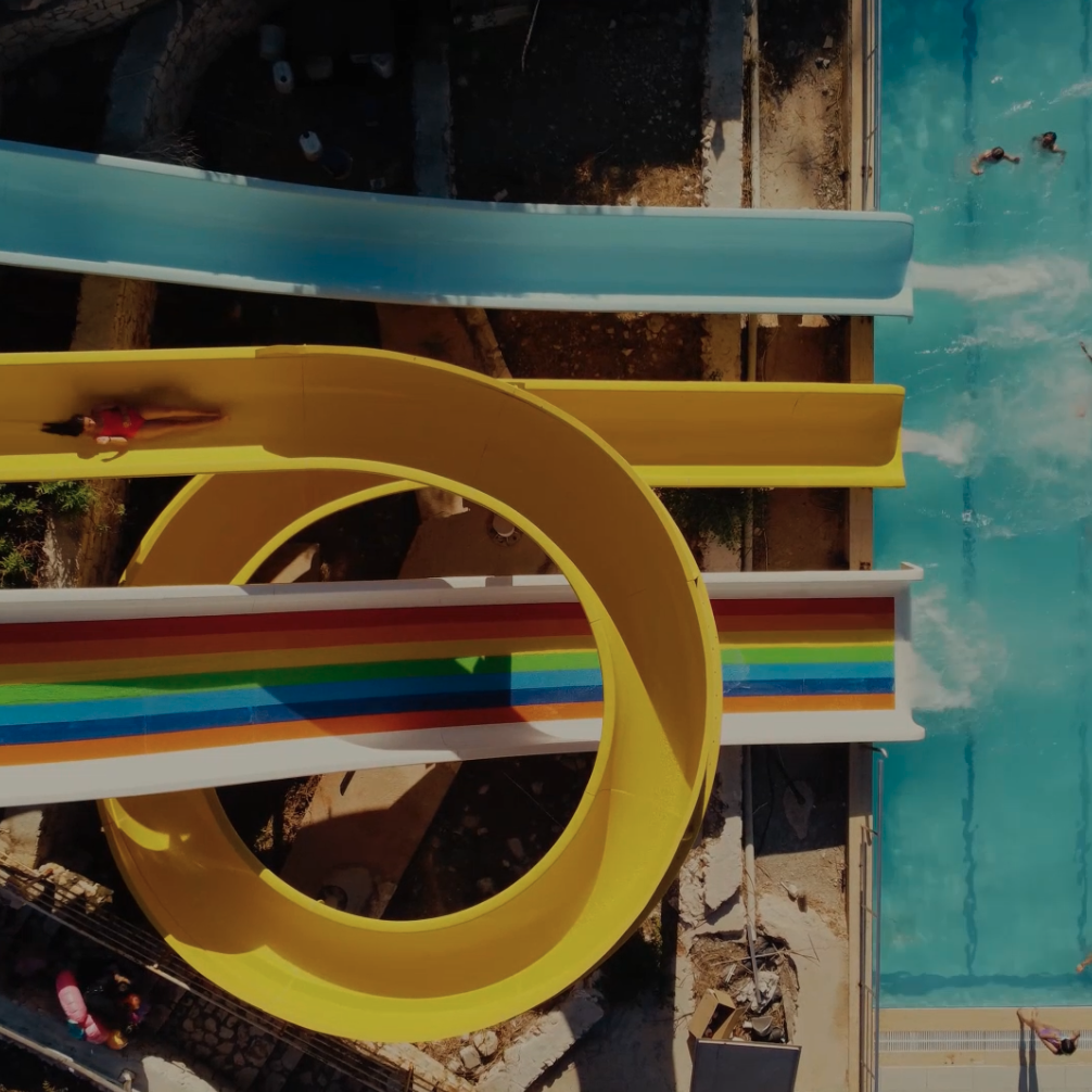 Aerial view of a set of water slides going into a large swimming pool.