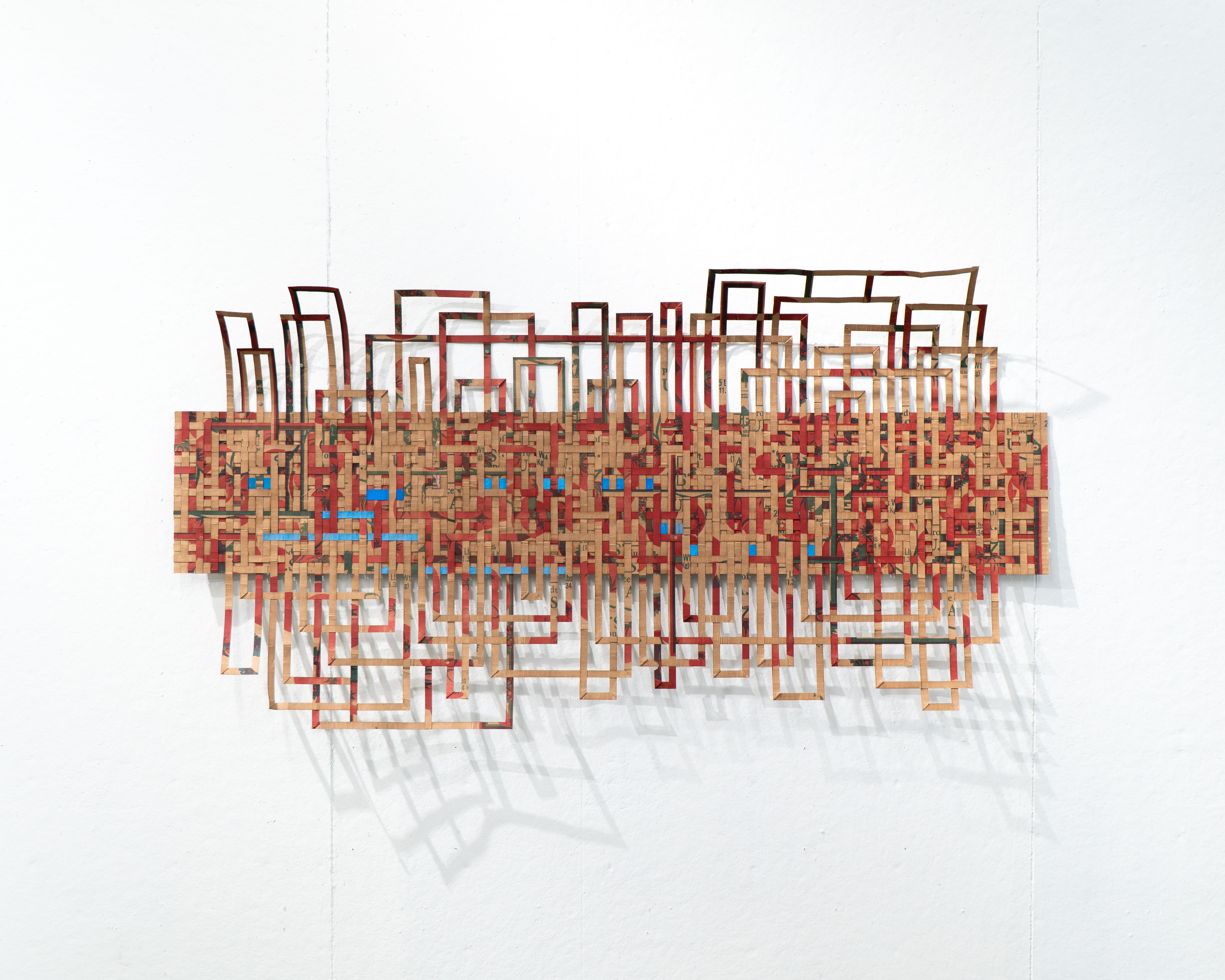Recycled paper material art, by Jill Stoll, on a blank wall.