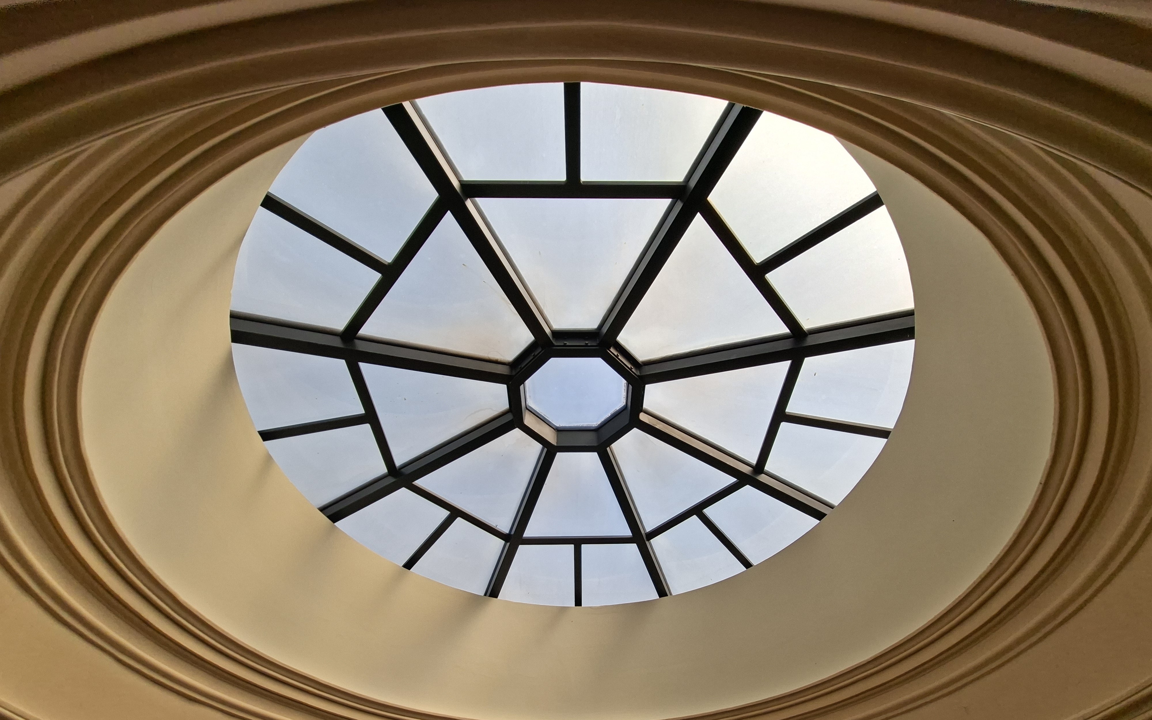 Shows the ceiling of the U.S. Treasury dome, with a circular skylight and crown molding around it