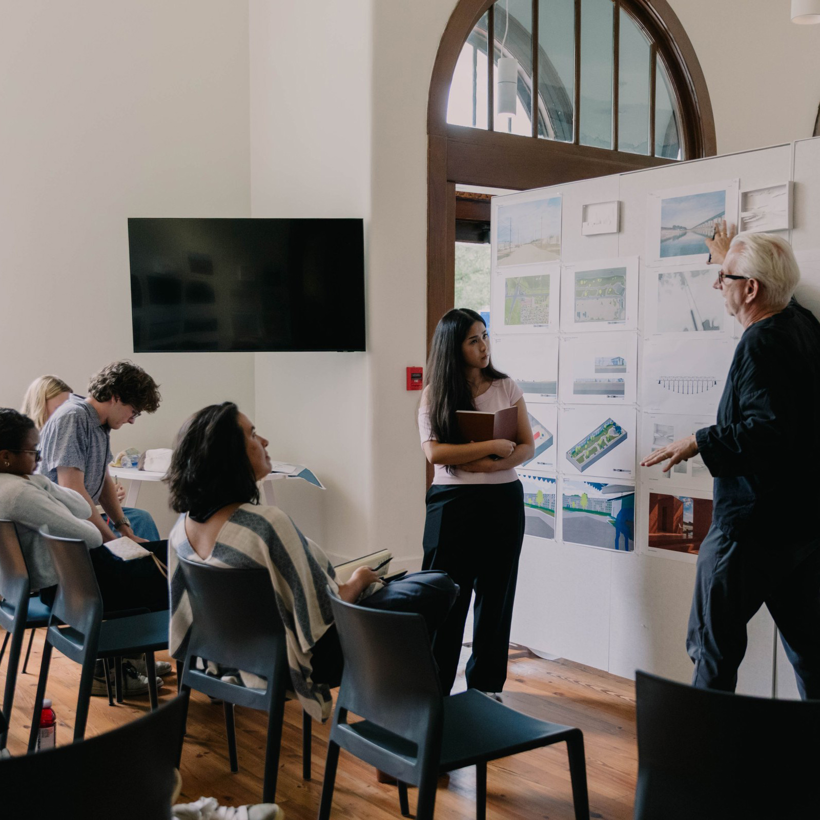 A professor talks to students during a design pinup session.