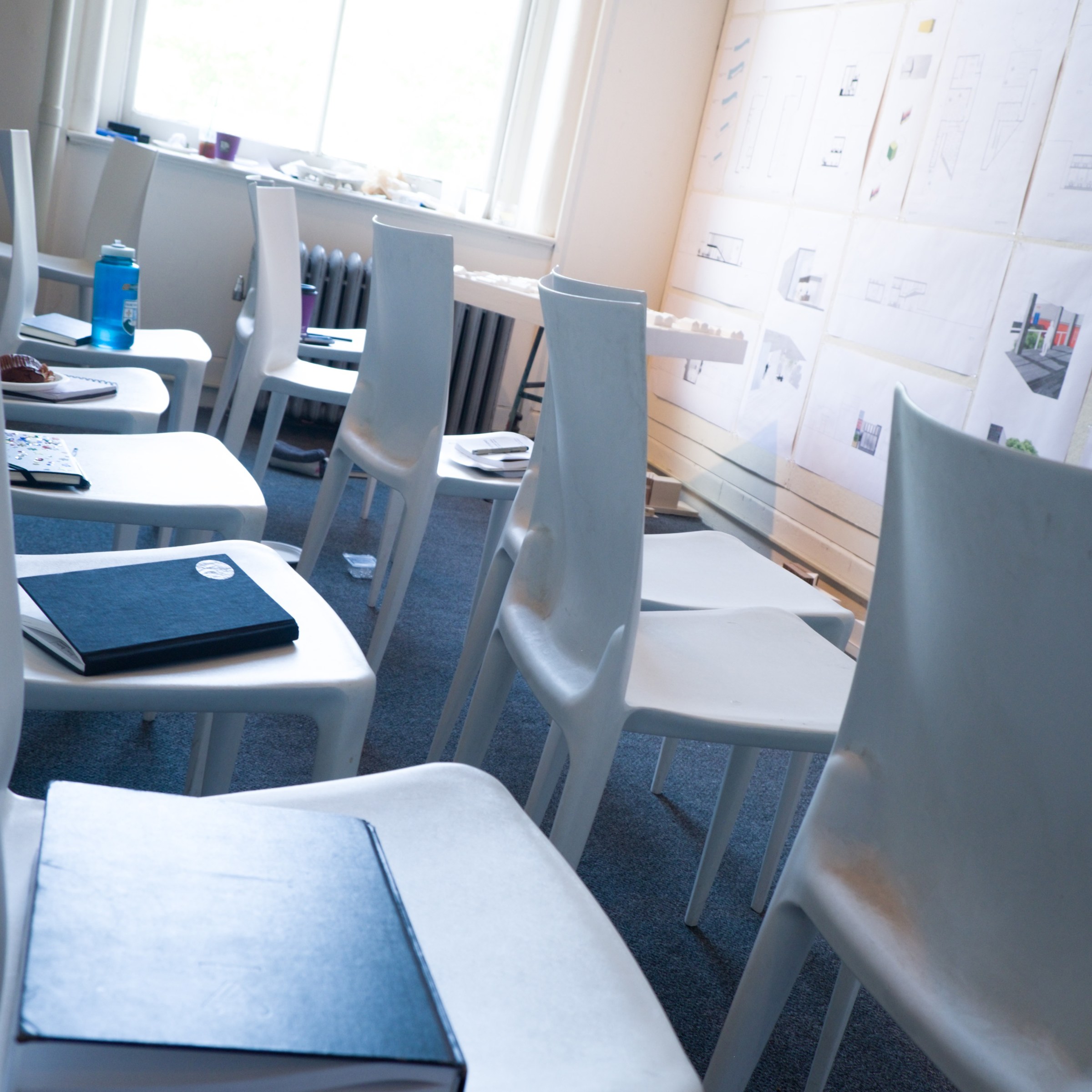 photo of two rows of empty chairs facing pinned up drawings on a wall