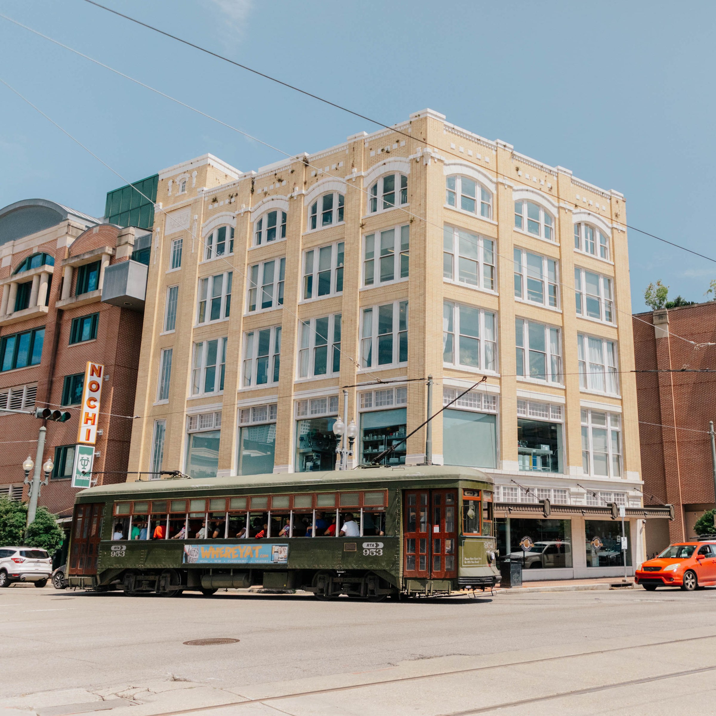 Exterior of five-story building on a corner in a downtown setting with a streetcar passing in the foreground